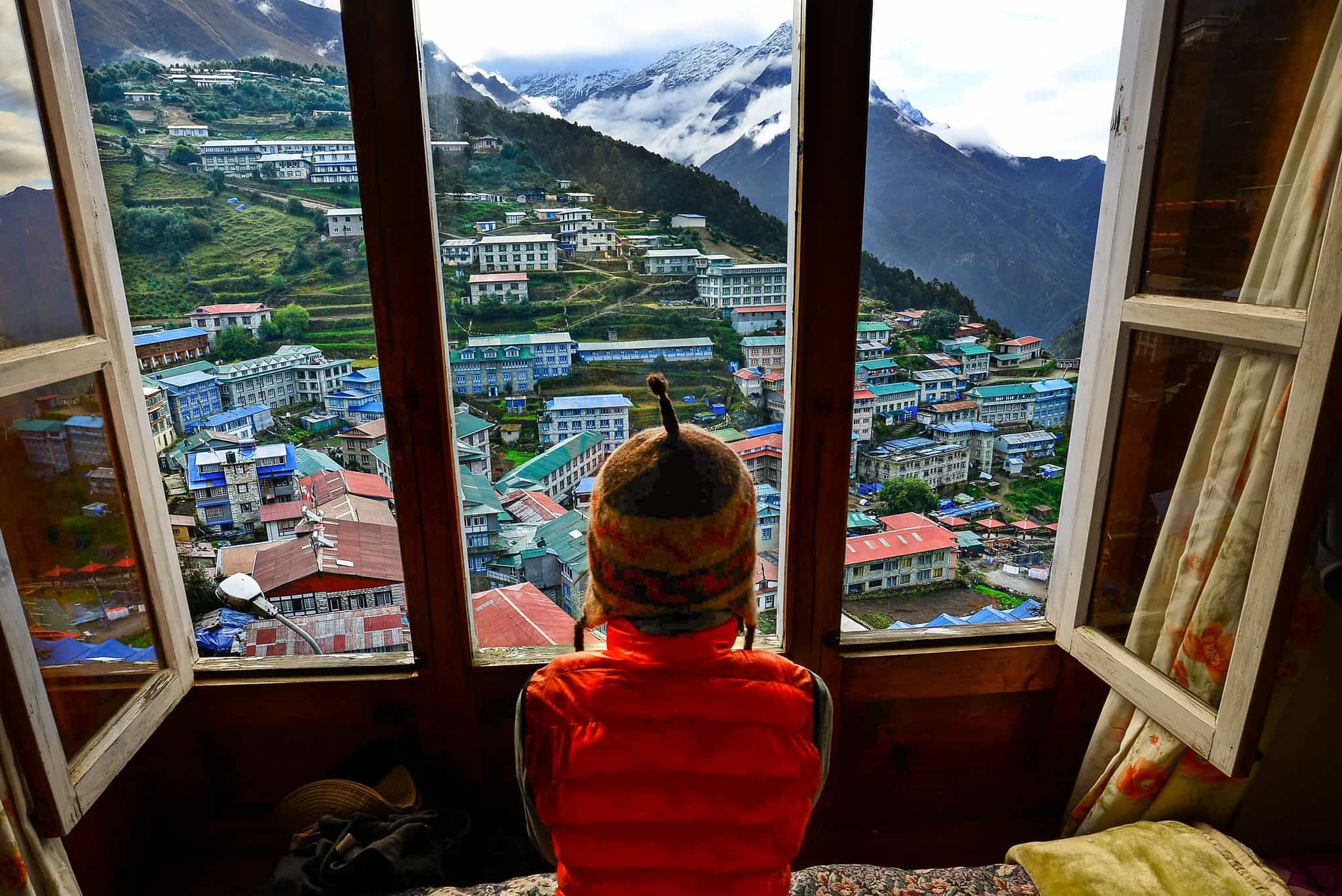 Female trekker looks out at the mountain views over Namche Bazaar from a teahouse