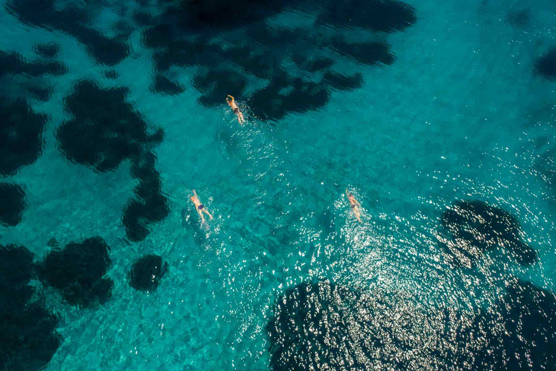 Three people swimming in crystal clear water of Meganisi, Greece