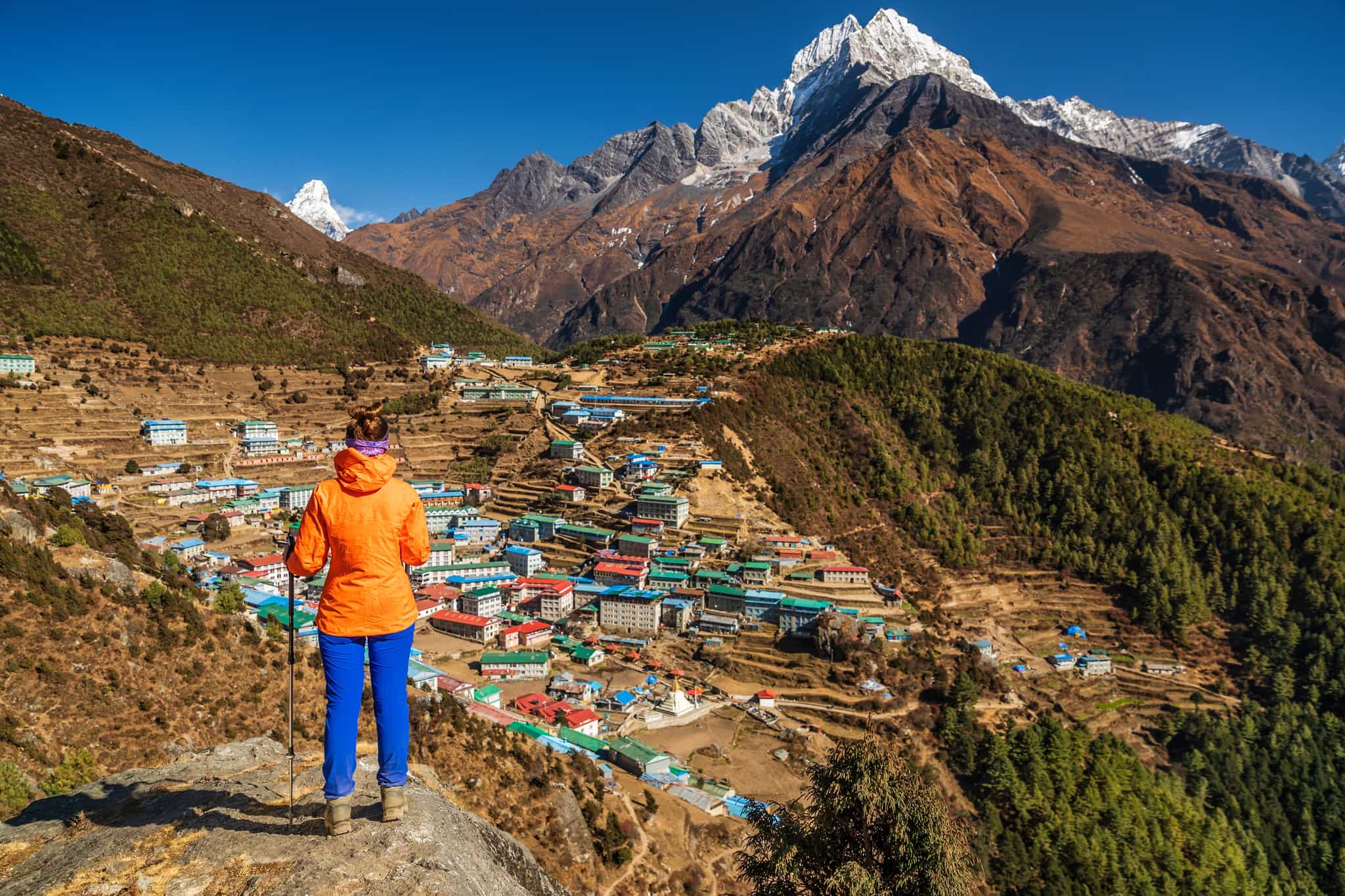 Hiker overlooks the mountain town of Namche Bazar with mountain backdrop