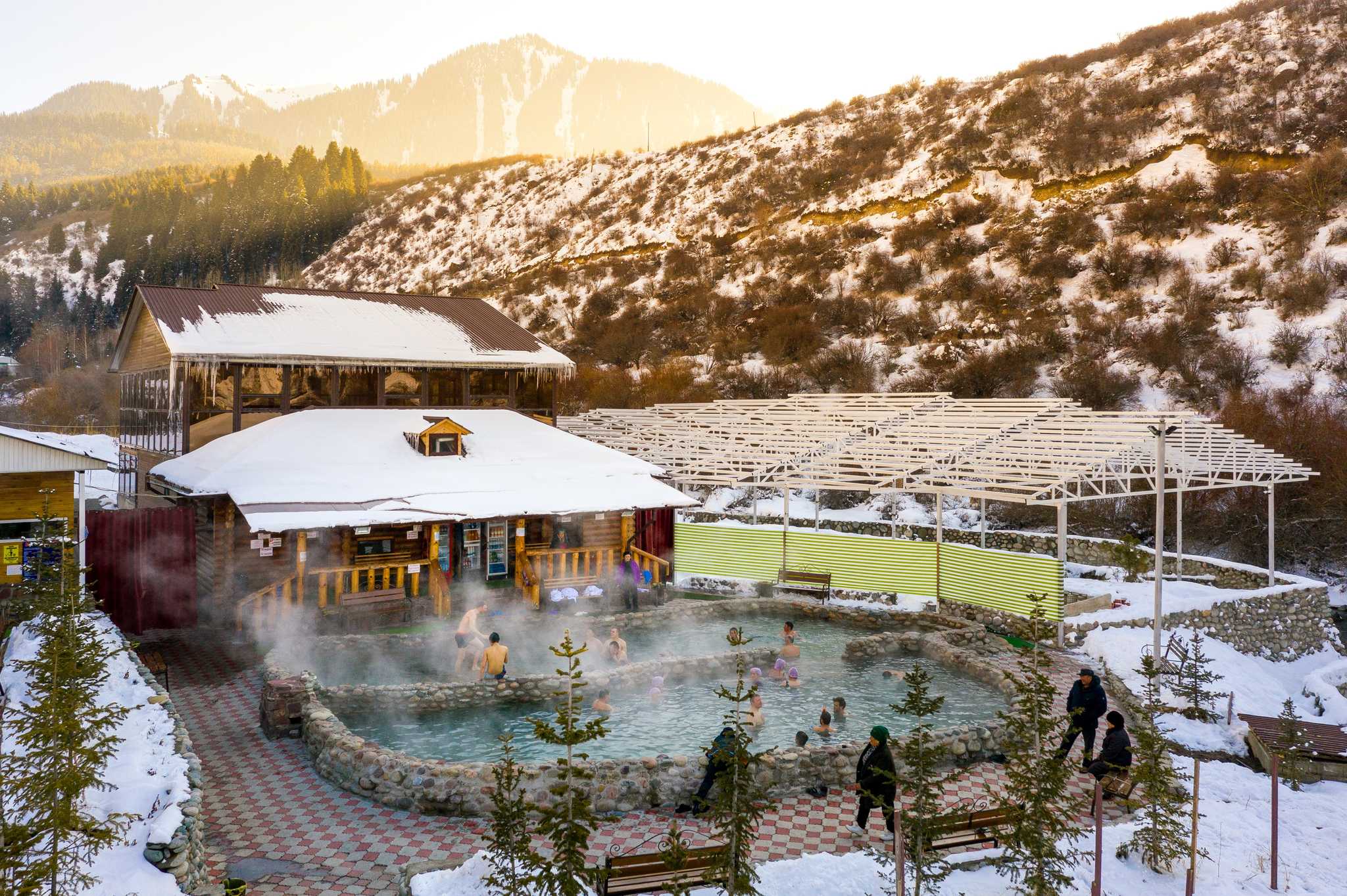 People enjoying the Kermet Suu hot springs below the snowy mountains of Kyrgyzstan