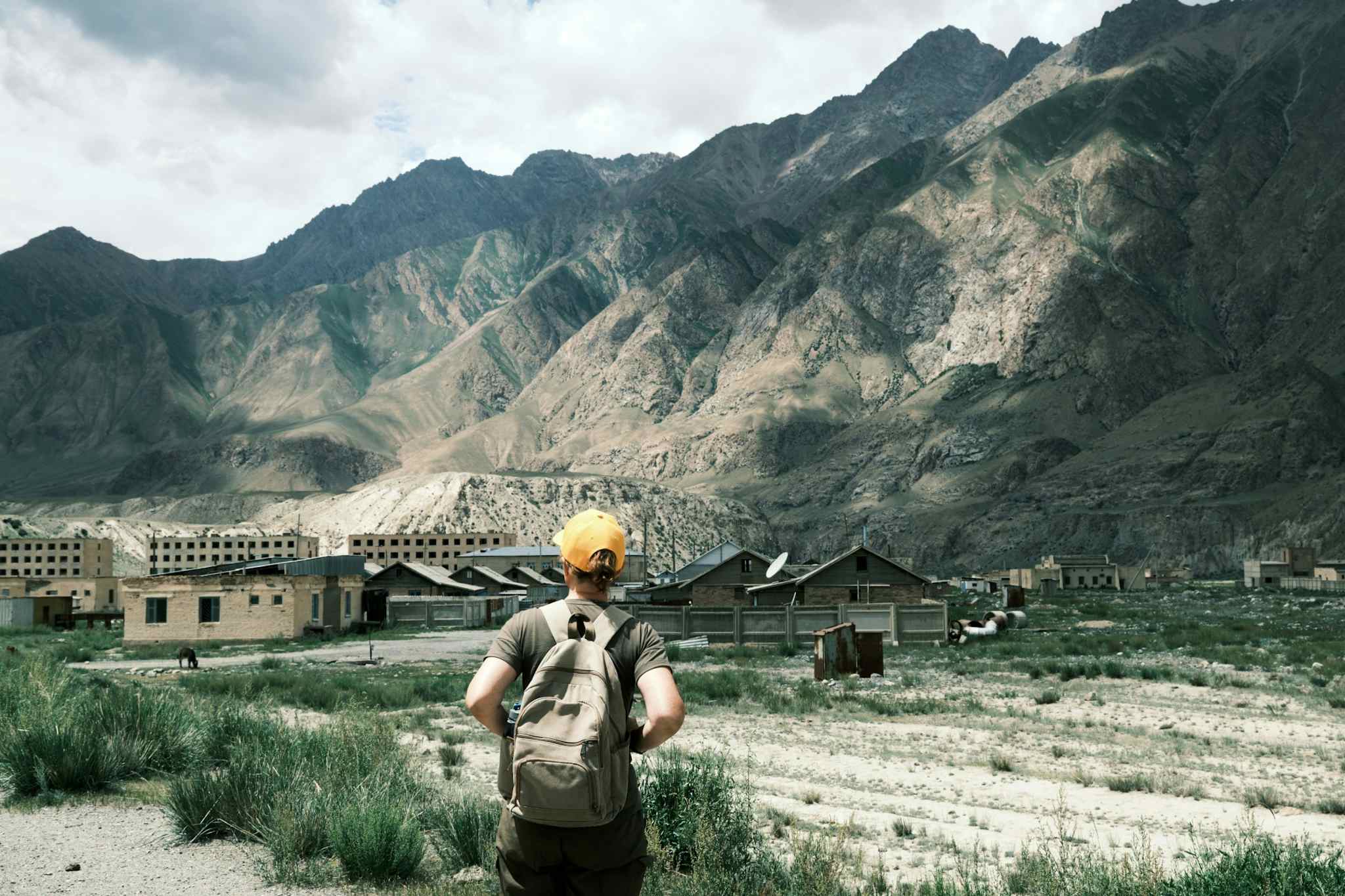 Backpacker overlooks the abandoned ghost town of Enylcheck in Kyrgyzstan
