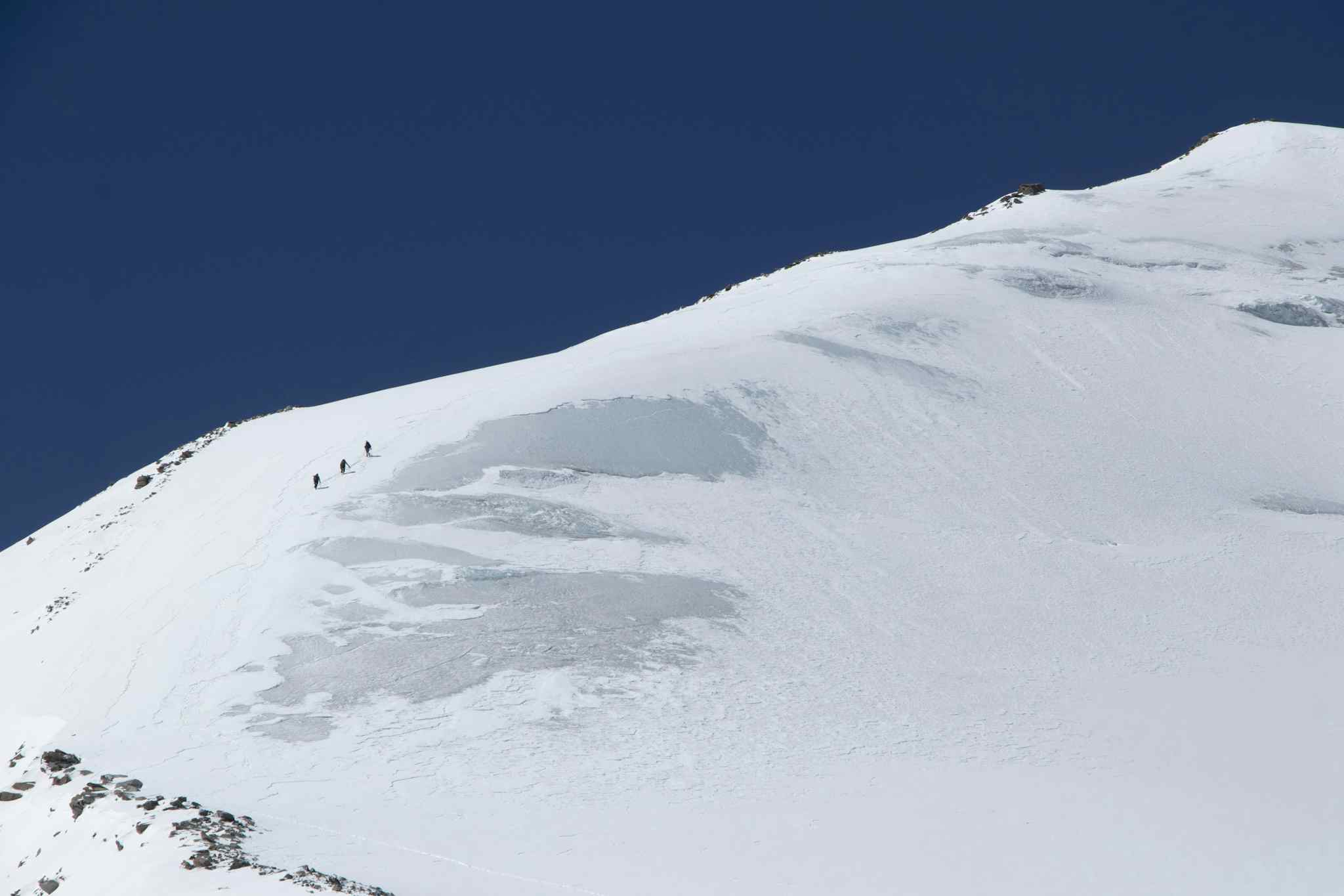 Three climbers ascending a snowy ridge to UT Kangri's peak, India