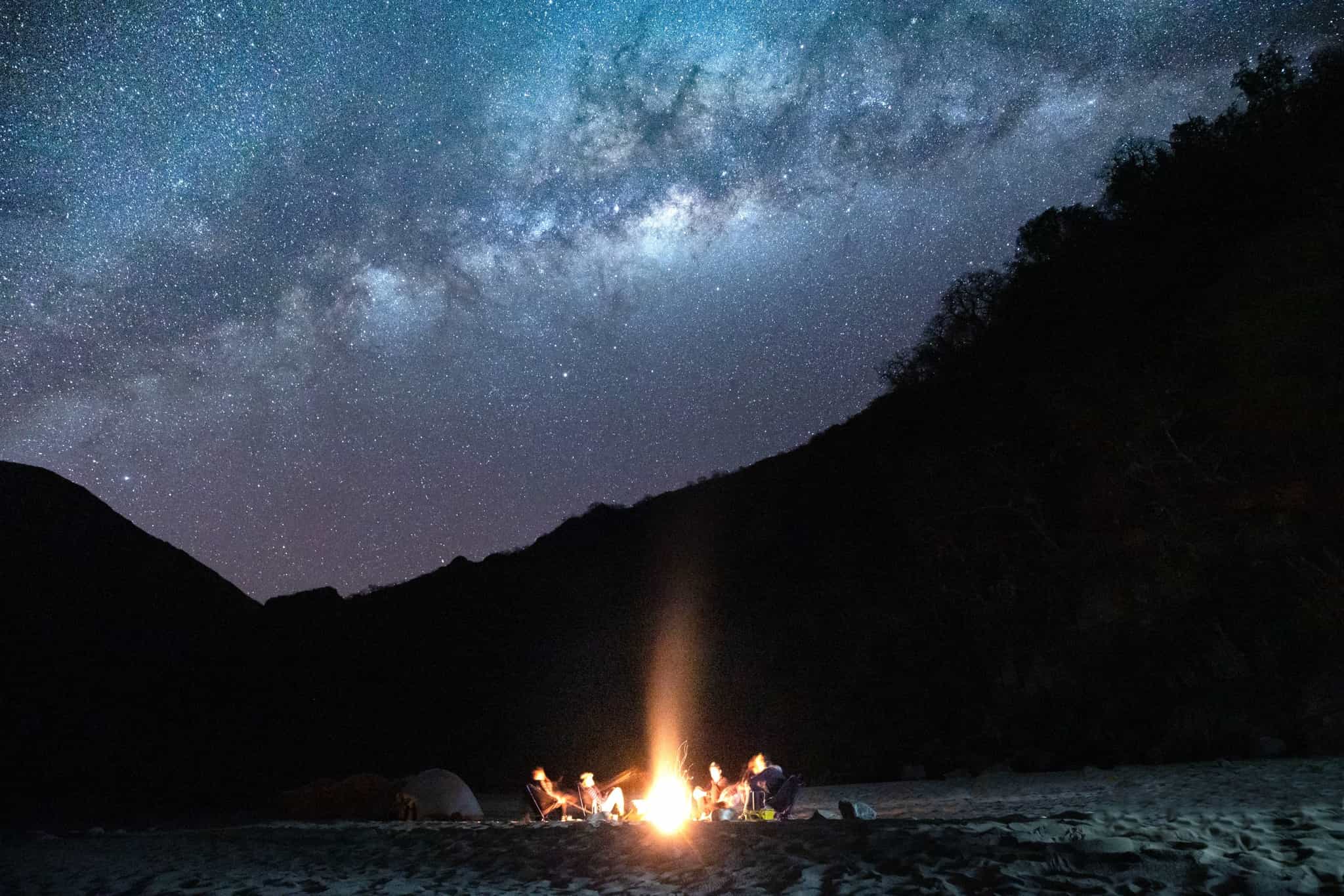 Firelit camp on the shore of Lake Pomacanchi under the Milky Way in Peru.