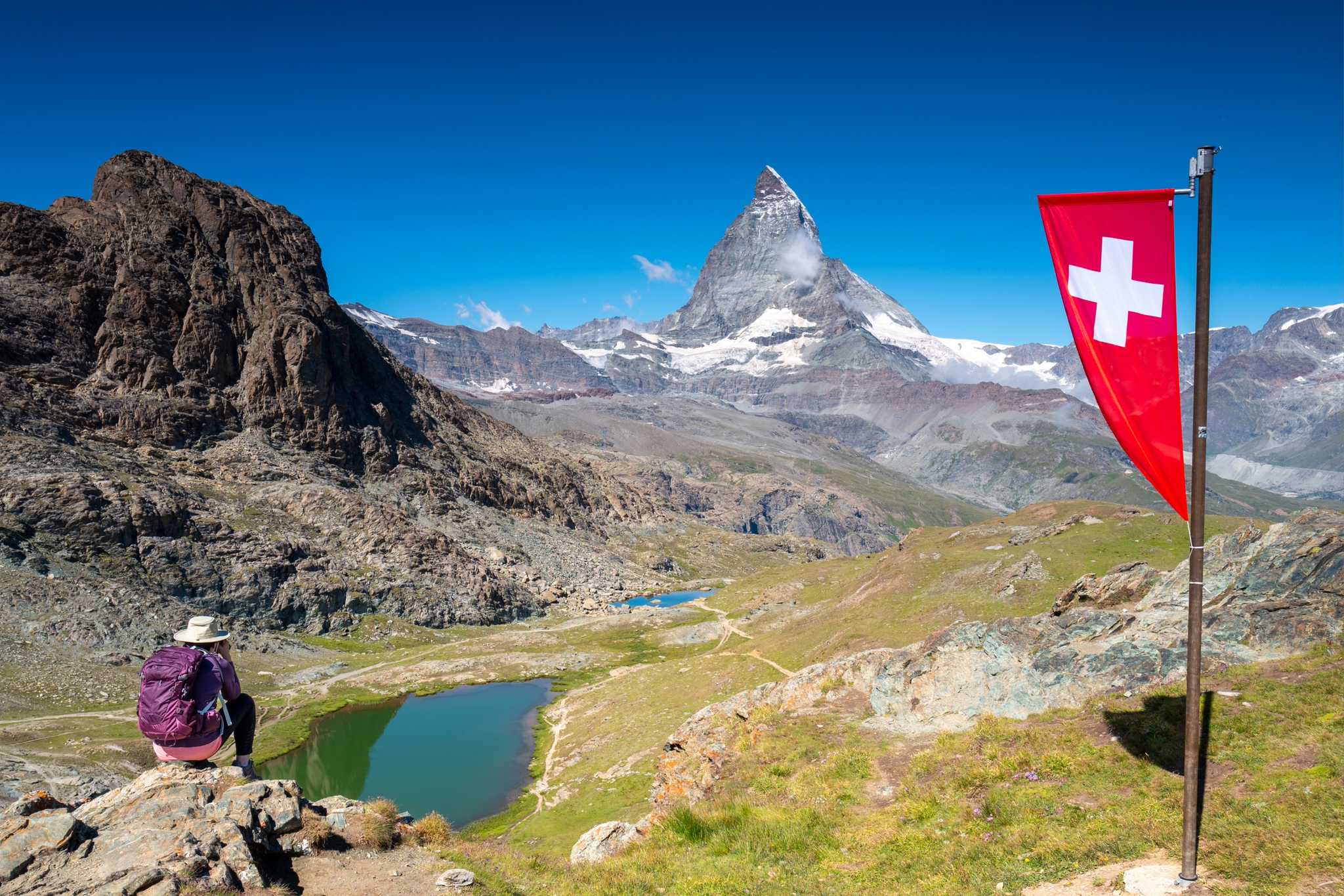 Hiker sits above Rifflesee with views of the Matterhorn