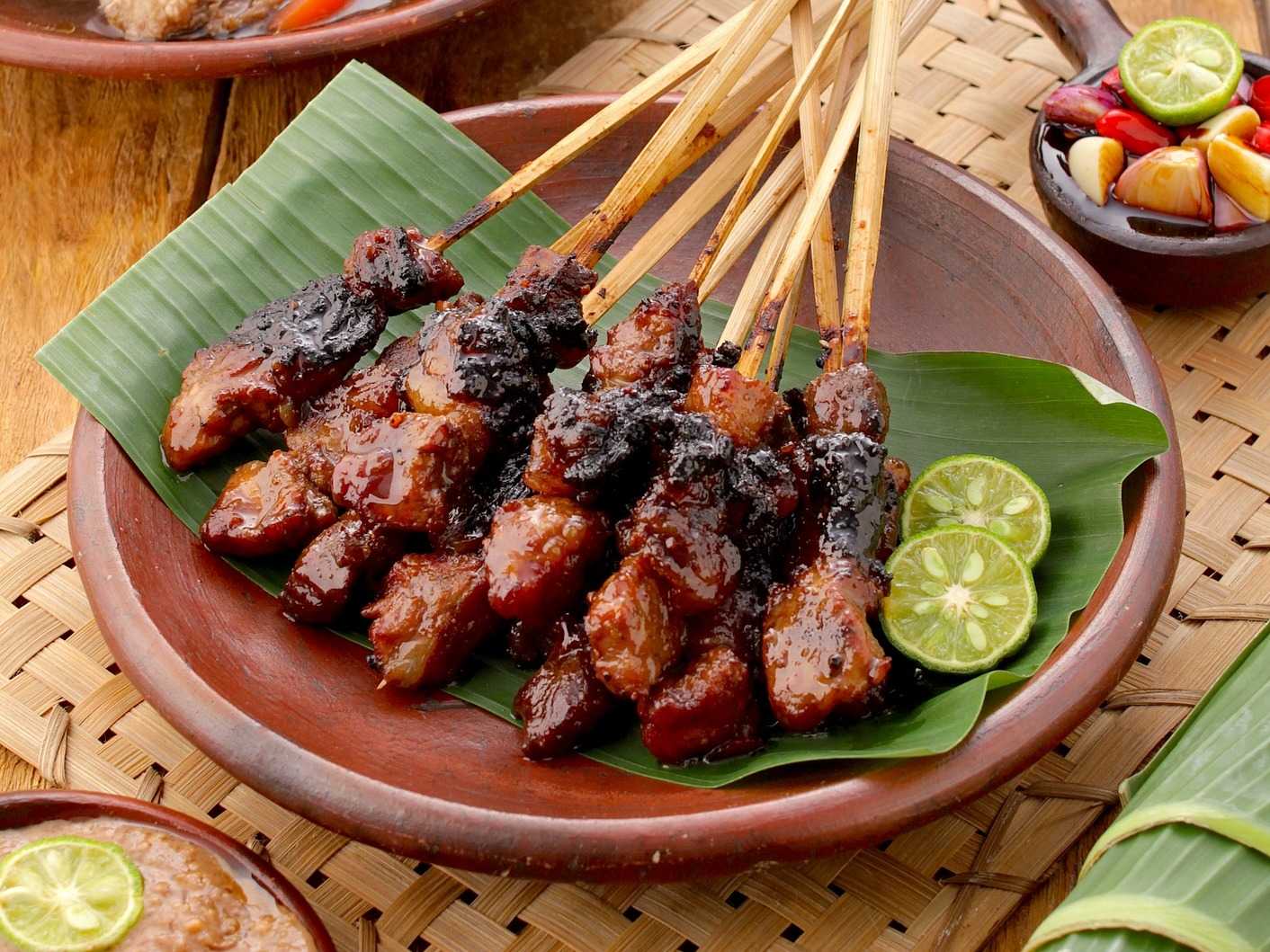 Skewered meat on a brown bowl with citrus fruits on the side