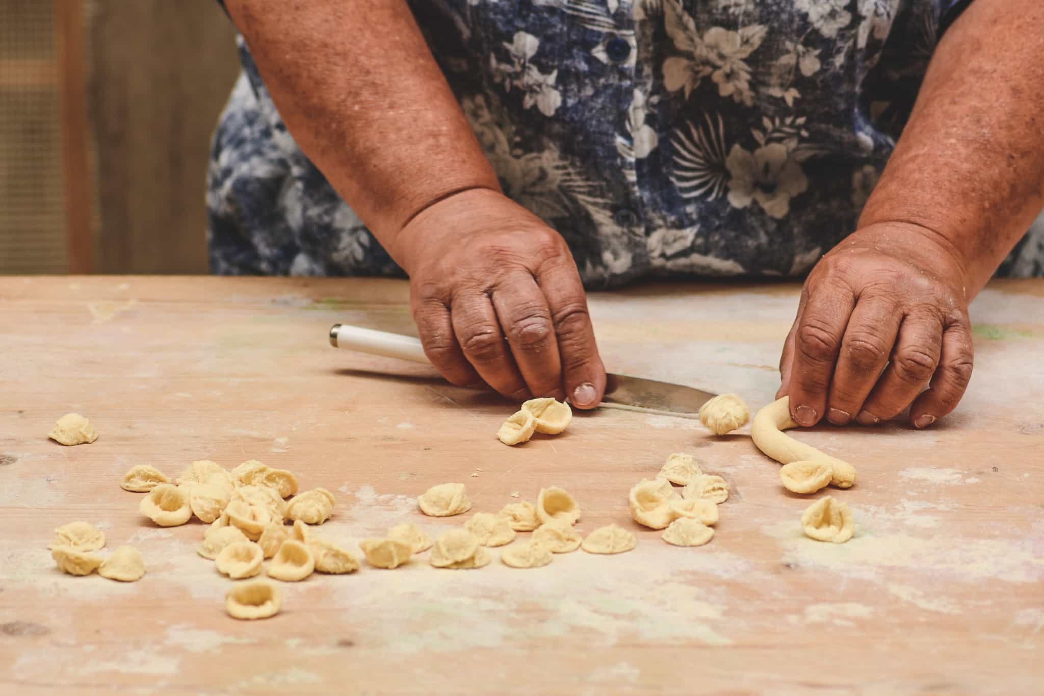 Close up of a woman's hands as she makes orecchiette pasta.