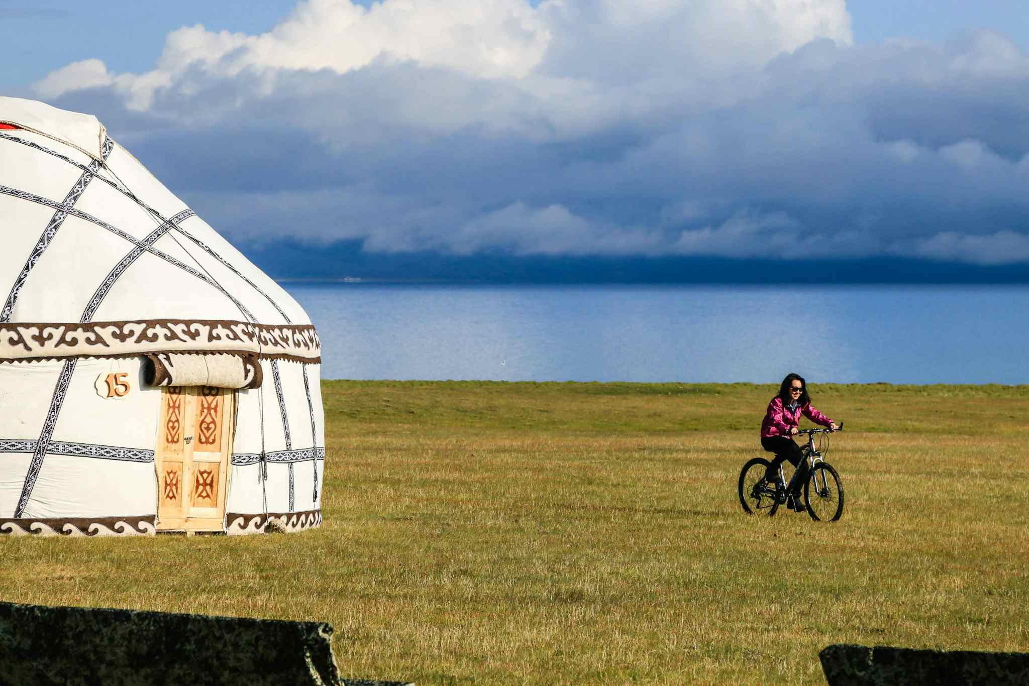 Cyclist riding by a yurt at Song Kul lake in Kyrgyzstan