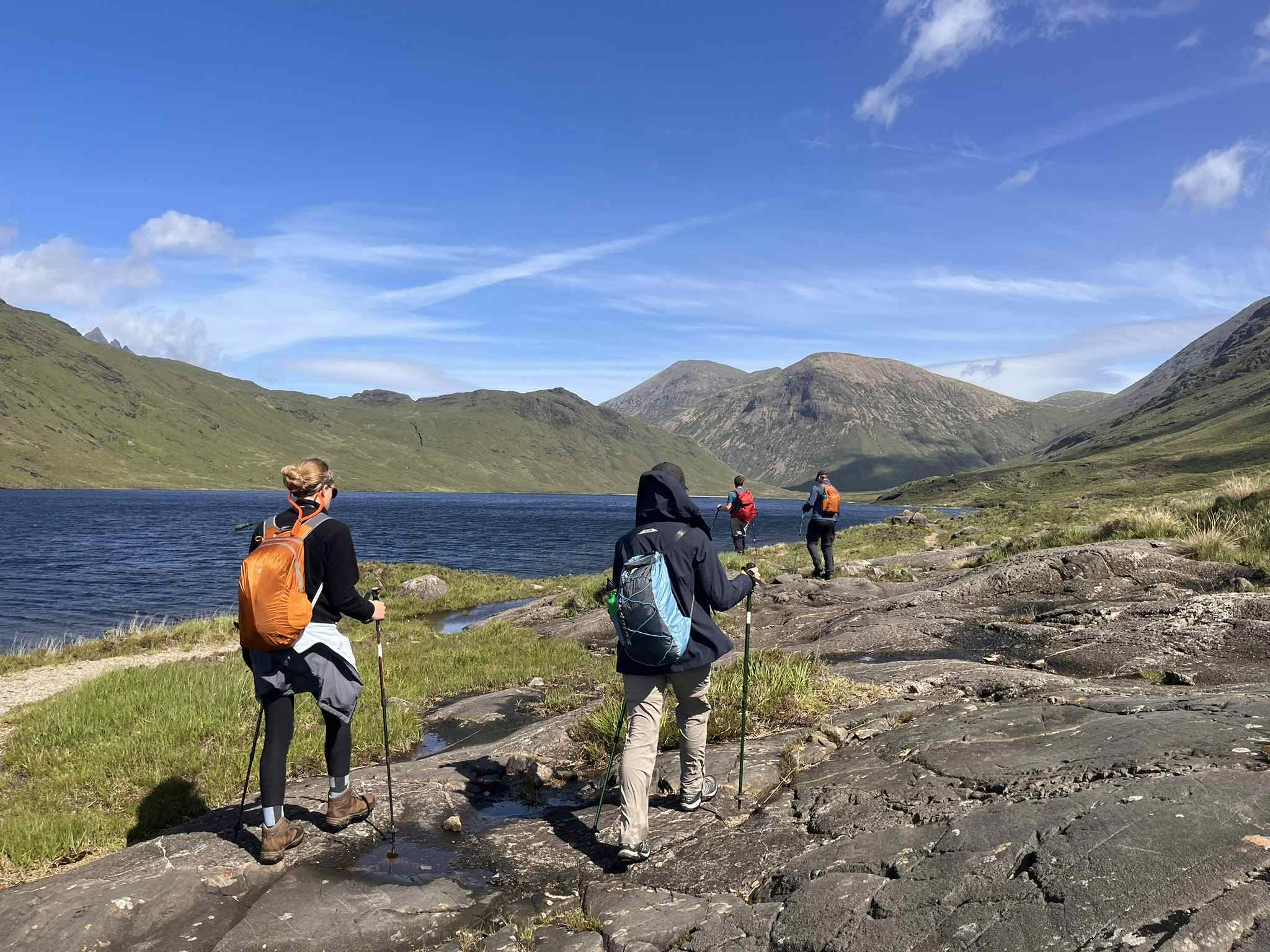 Hikers on the Isle of Skye by a loch on a sunny day, Scotland