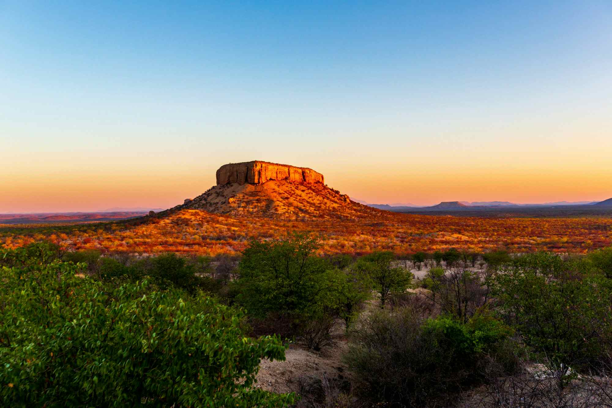The rich, red Waterberg Plateau in Namibia against the horizon at sunset