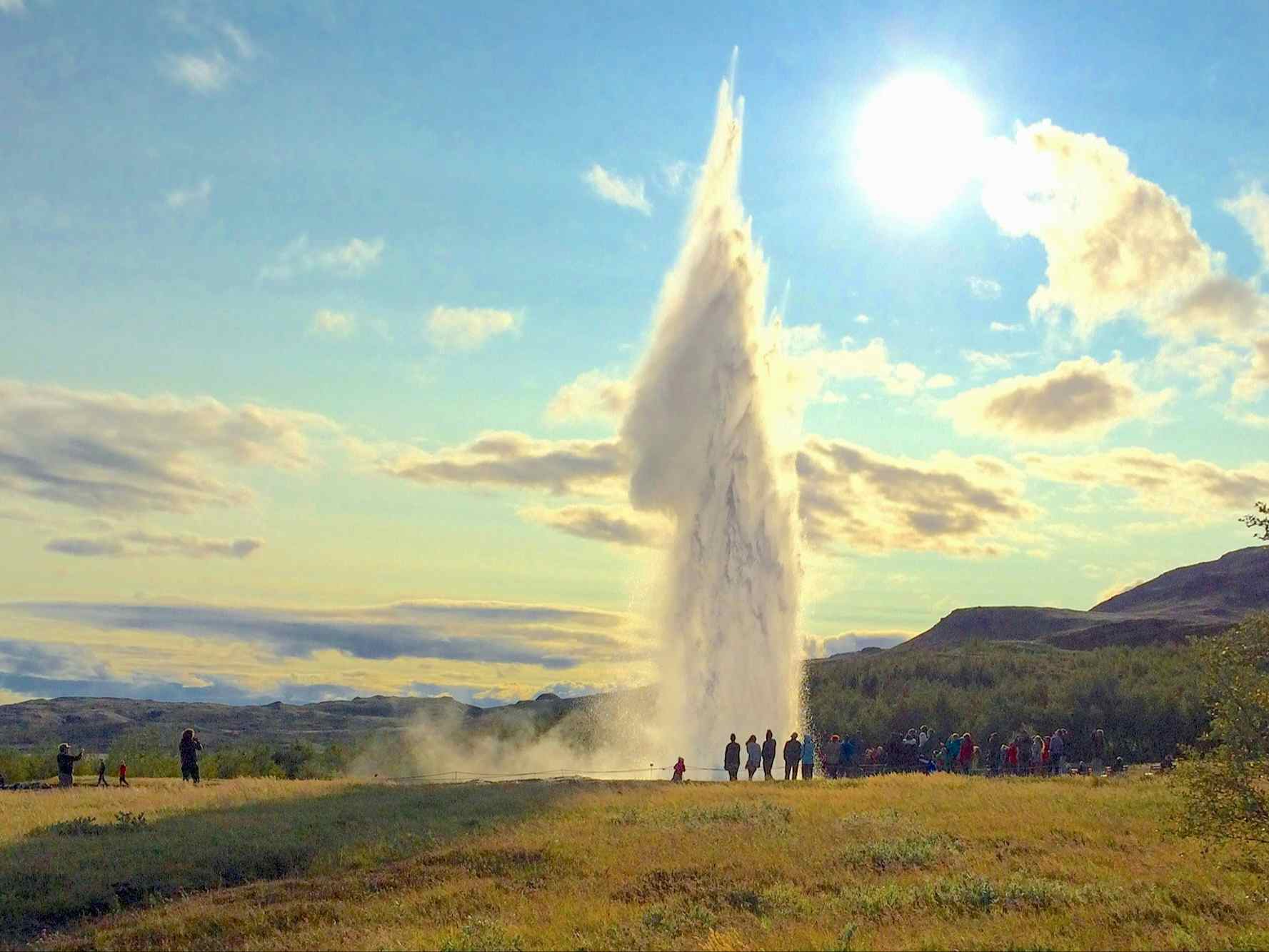 People silhoutted against a geyser erupting in Iceland
