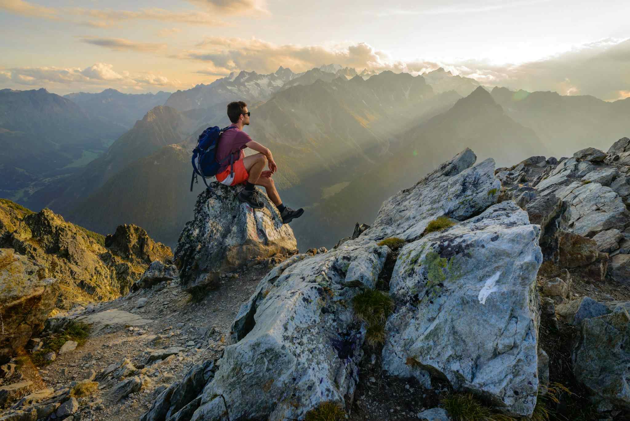 Man sits on a rock overlooking the Alps