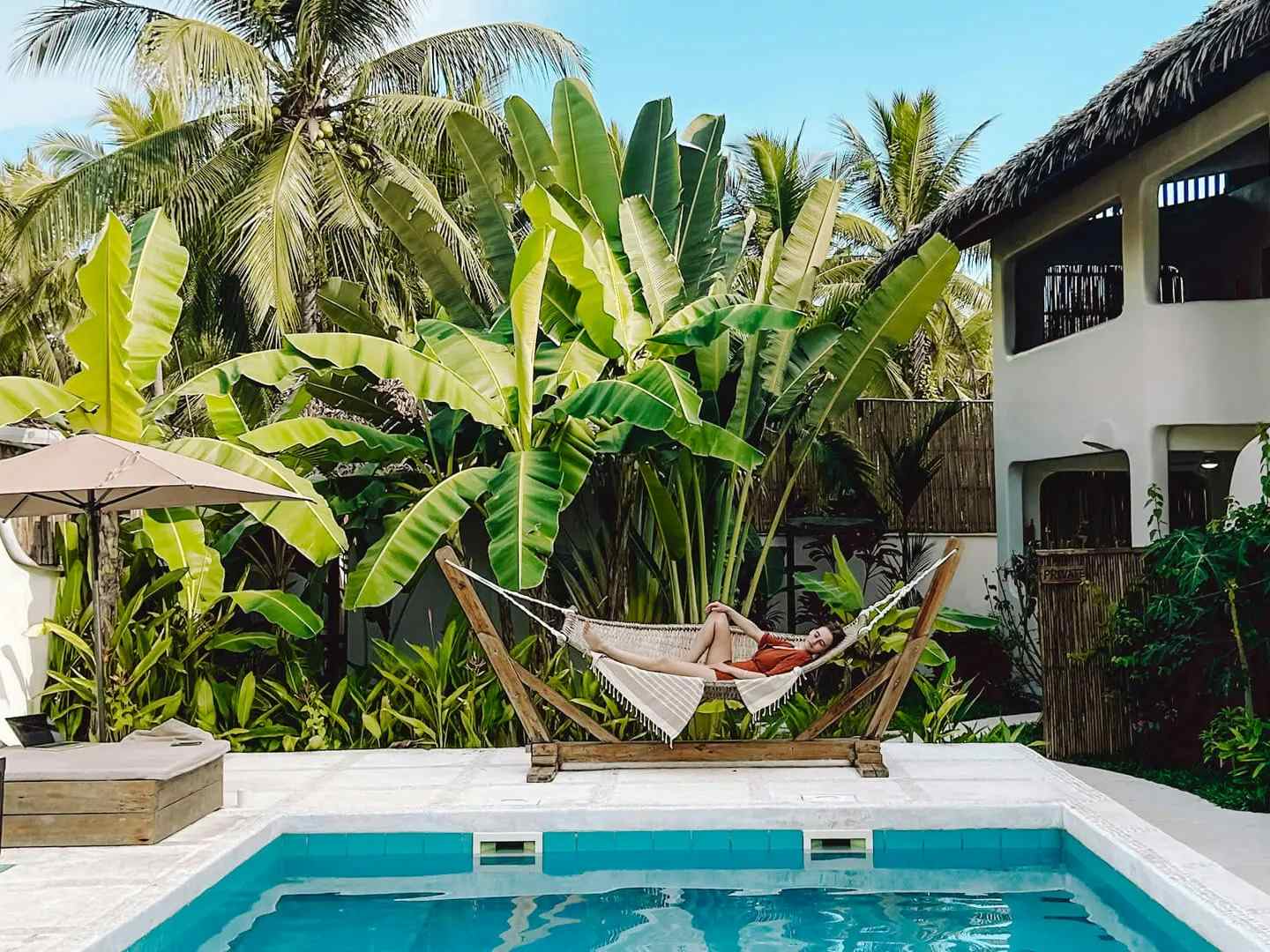 Woman lying in a hammock by a pool 