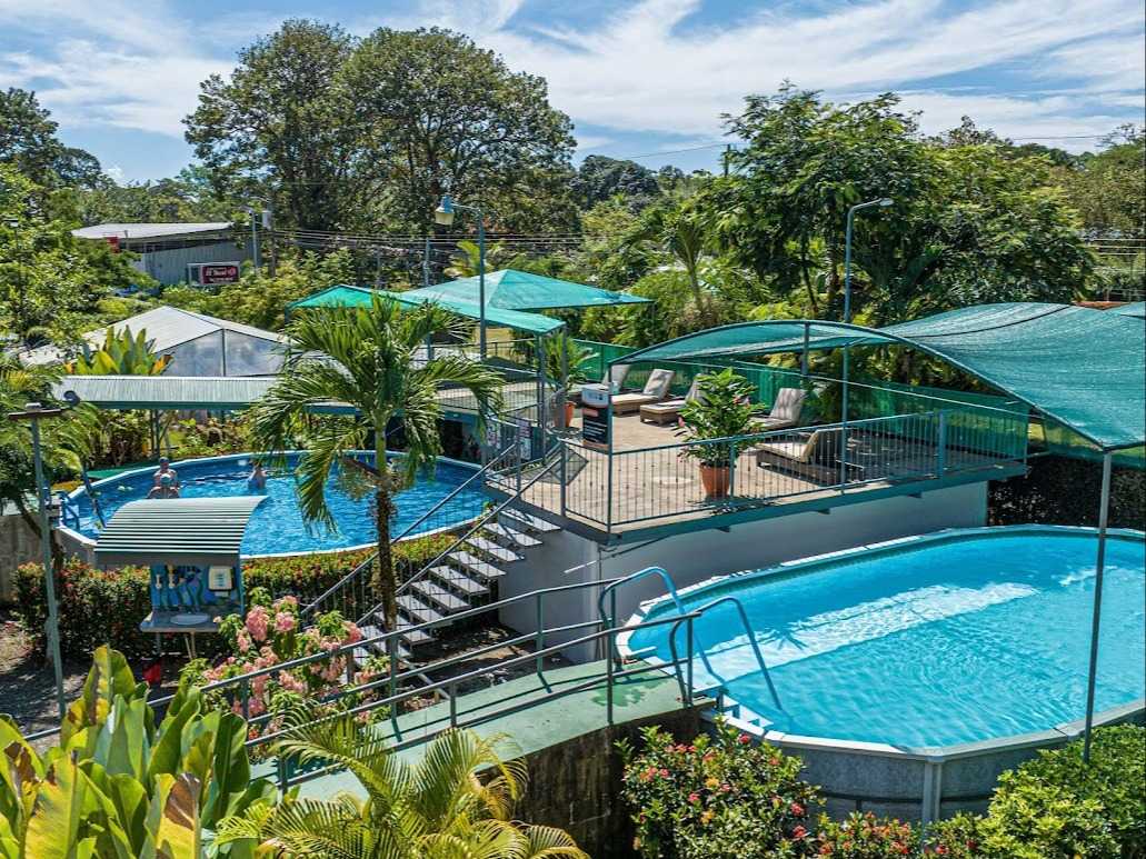 Two swimming pools with green covered shades and sun terrace