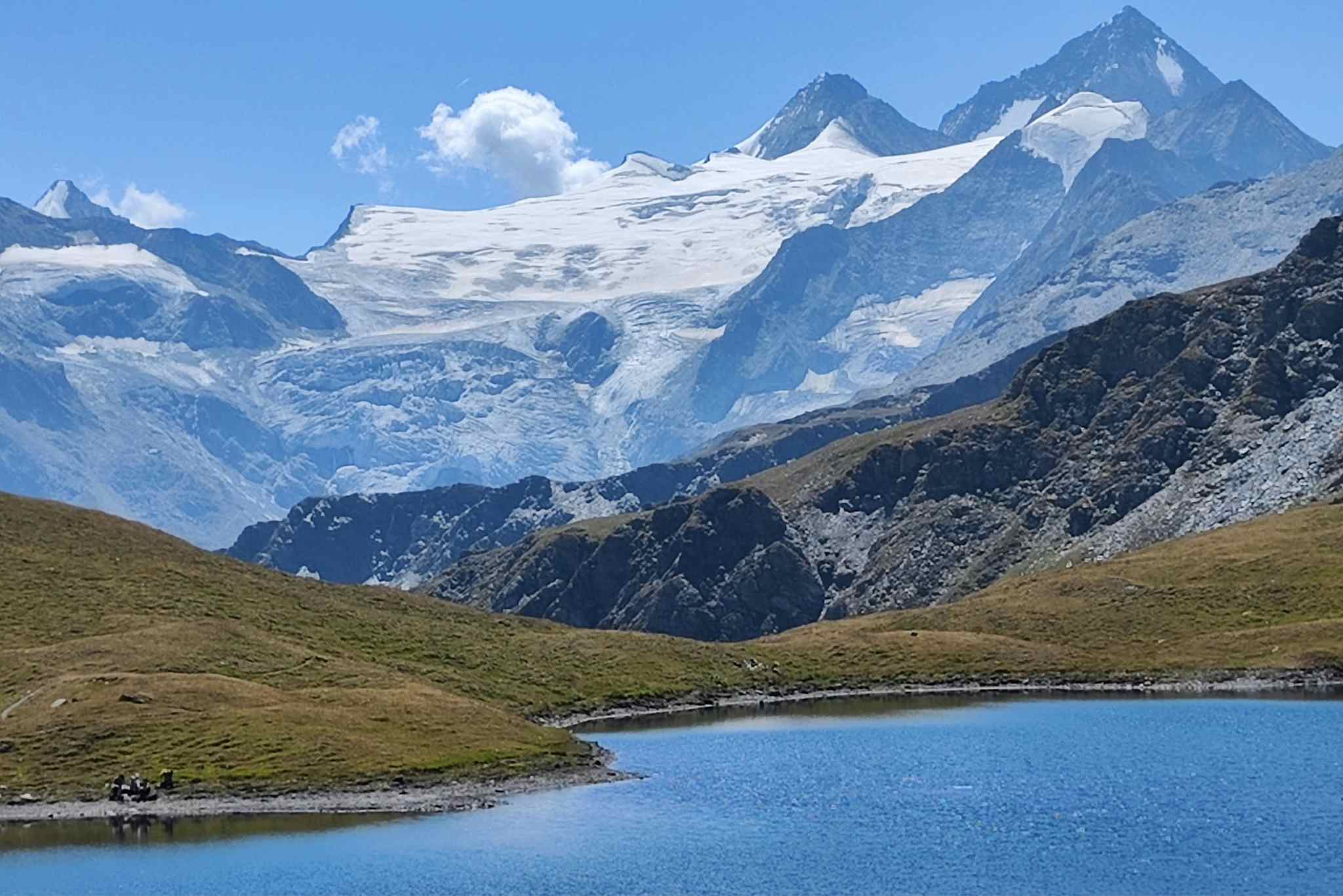 Couple relaxing by a high alpine lake with 4000m peaks in the background