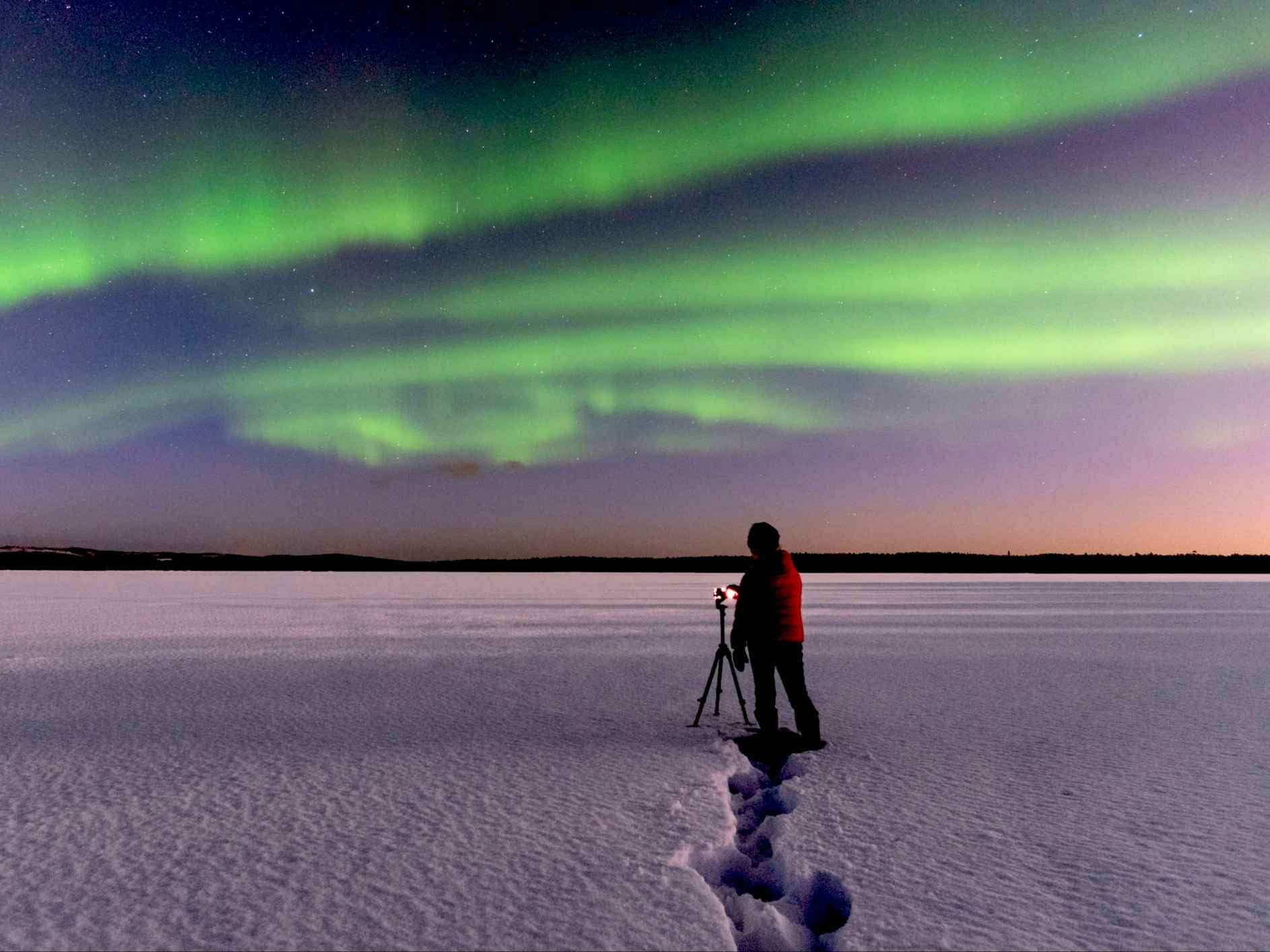 Man taking photos of the northern lights with tripod in Lapland.