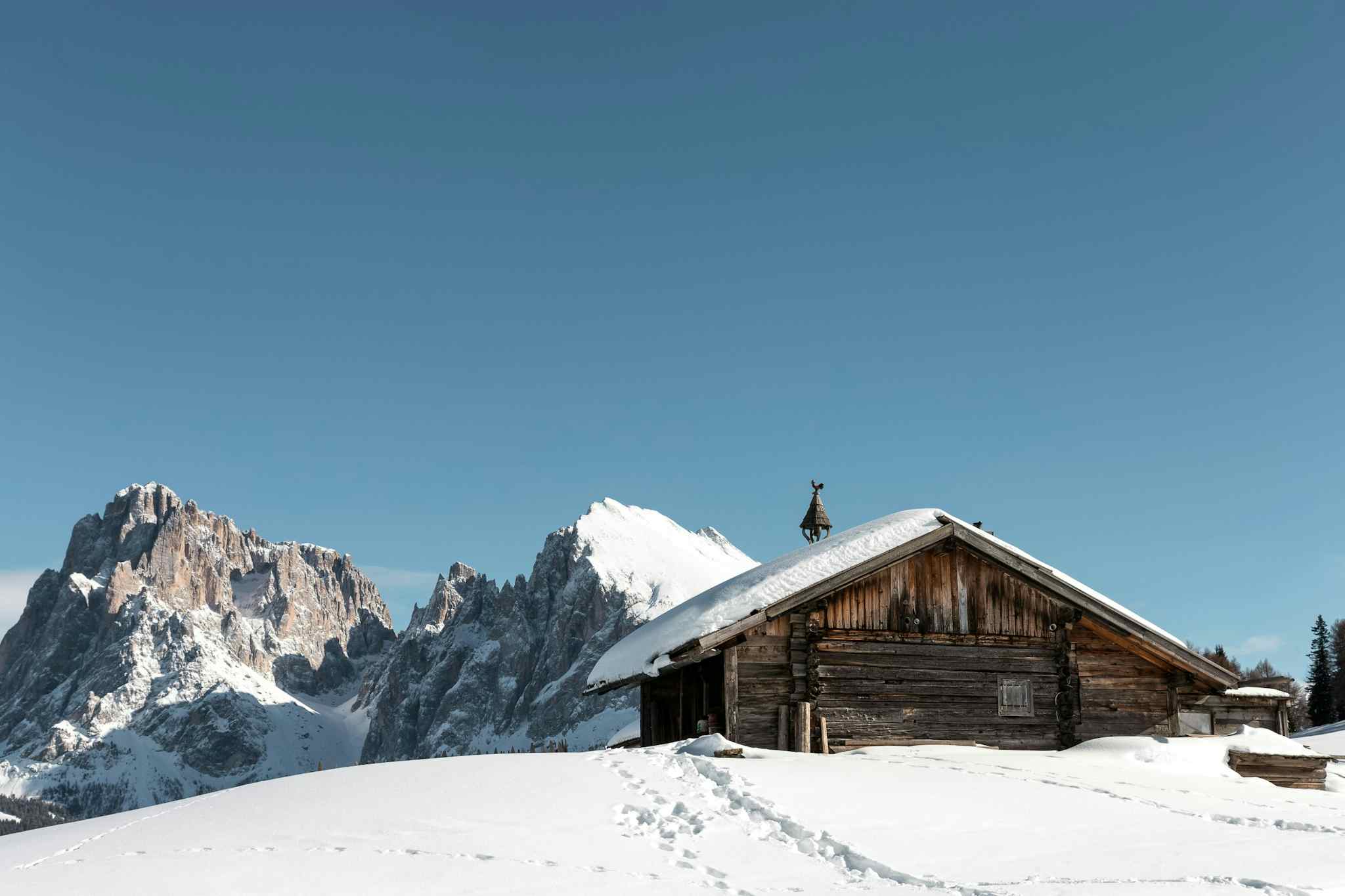 Snow-covered hut with the jagged Dolomite Mountains in the background, Italy.