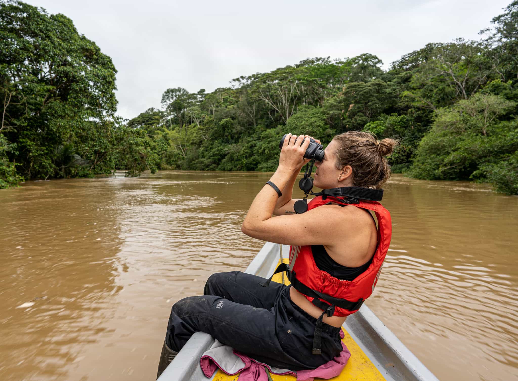 Woman on a boat on the Tiputini River with binoculars in Ecuador.