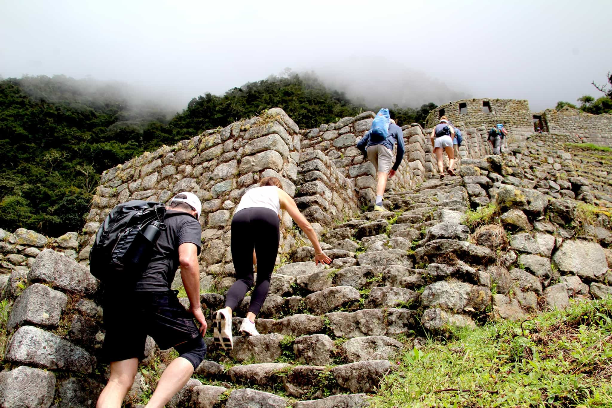 Hikers on the KM104 section of the Inca Trail climbing stone steps in Peru.