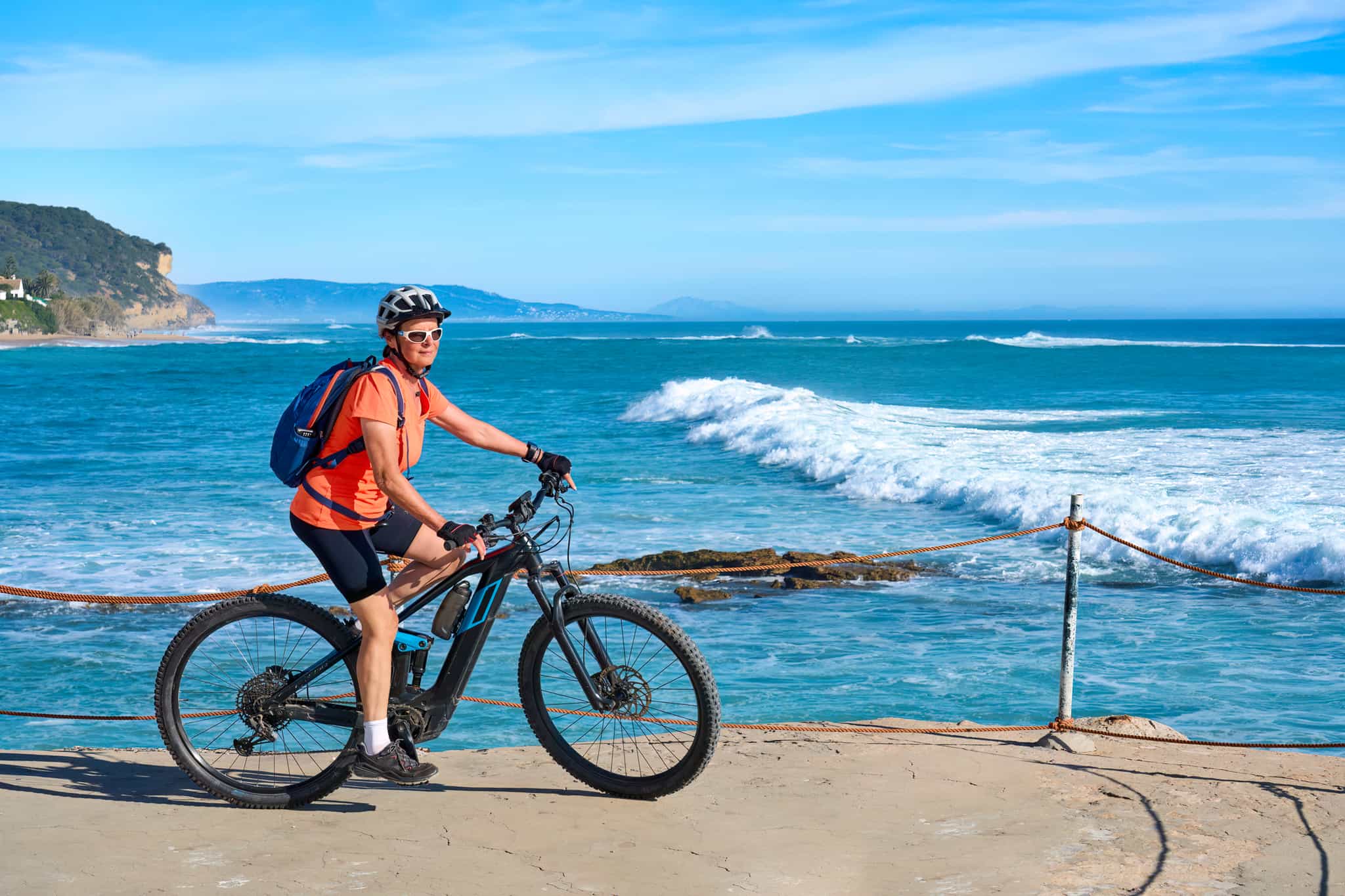 Woman cycling with her mountain bike at the beach of Cape Trafalgar, Costa de la Luz, Andalusia, Spain
