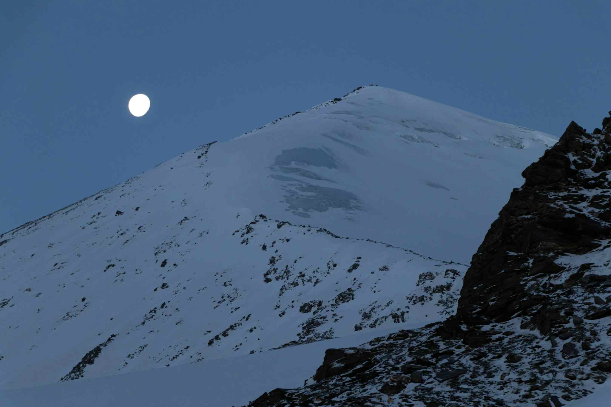 The moon over UT Kangri Peak at night in Ladakh, India