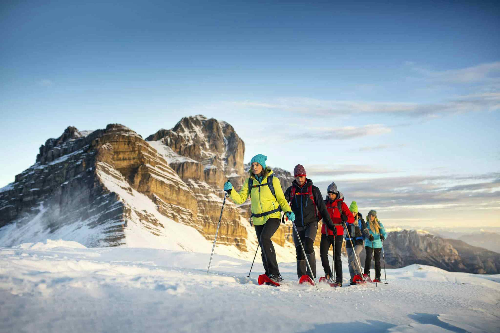 A group of hikers snowshoeing in front of the peaks of the Dolomites, Italy.