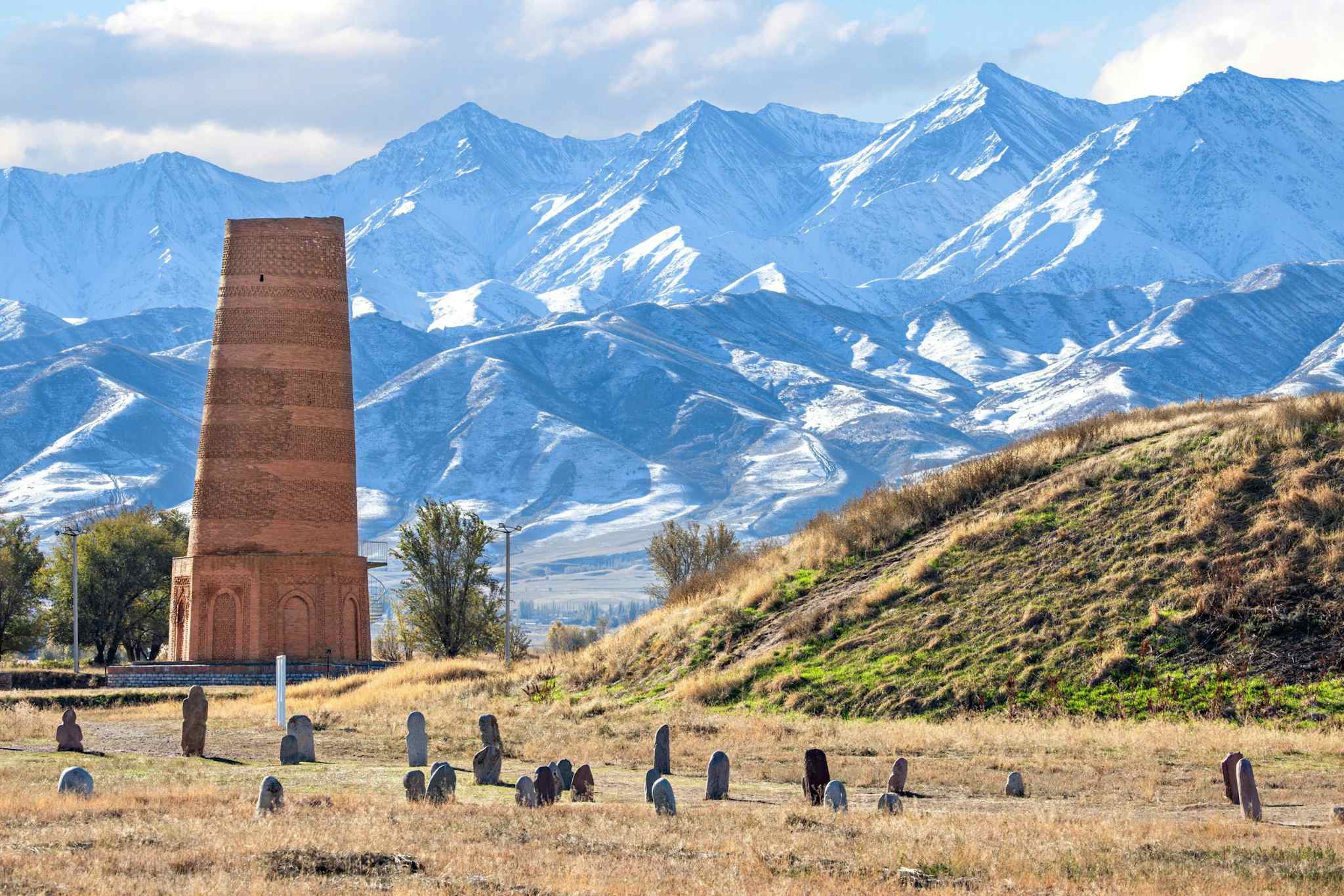 Burana Tower and the surrounding Babel stones, with snowy mountains behind, in Kyrgyzstan.