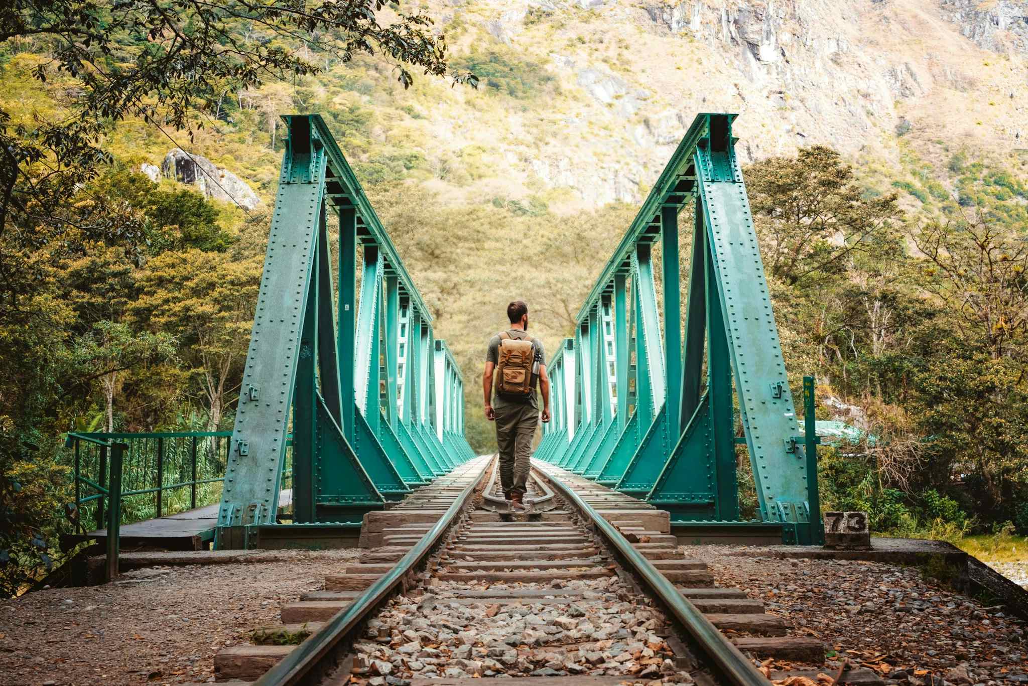 Man walking over train bridge on the way to Aguas Calientes in Peru.