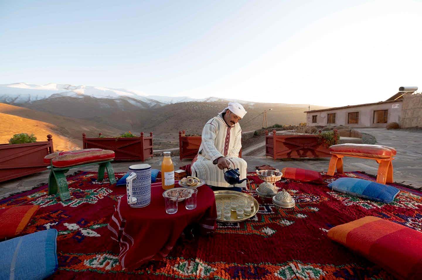 Local berber man pouring tea on a red rug in Atlas Mountains, Morocco