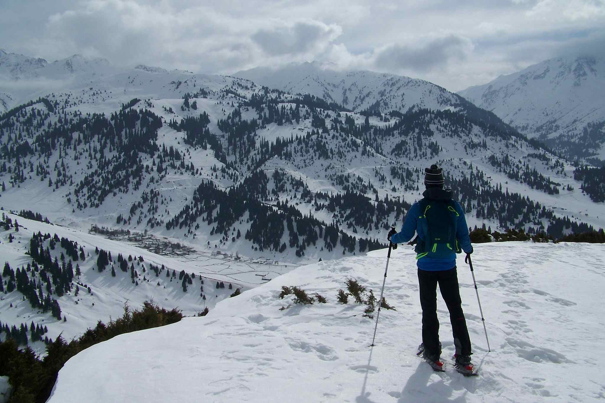 Solo snowshoer stands at a viewpoint overlooking the mountains