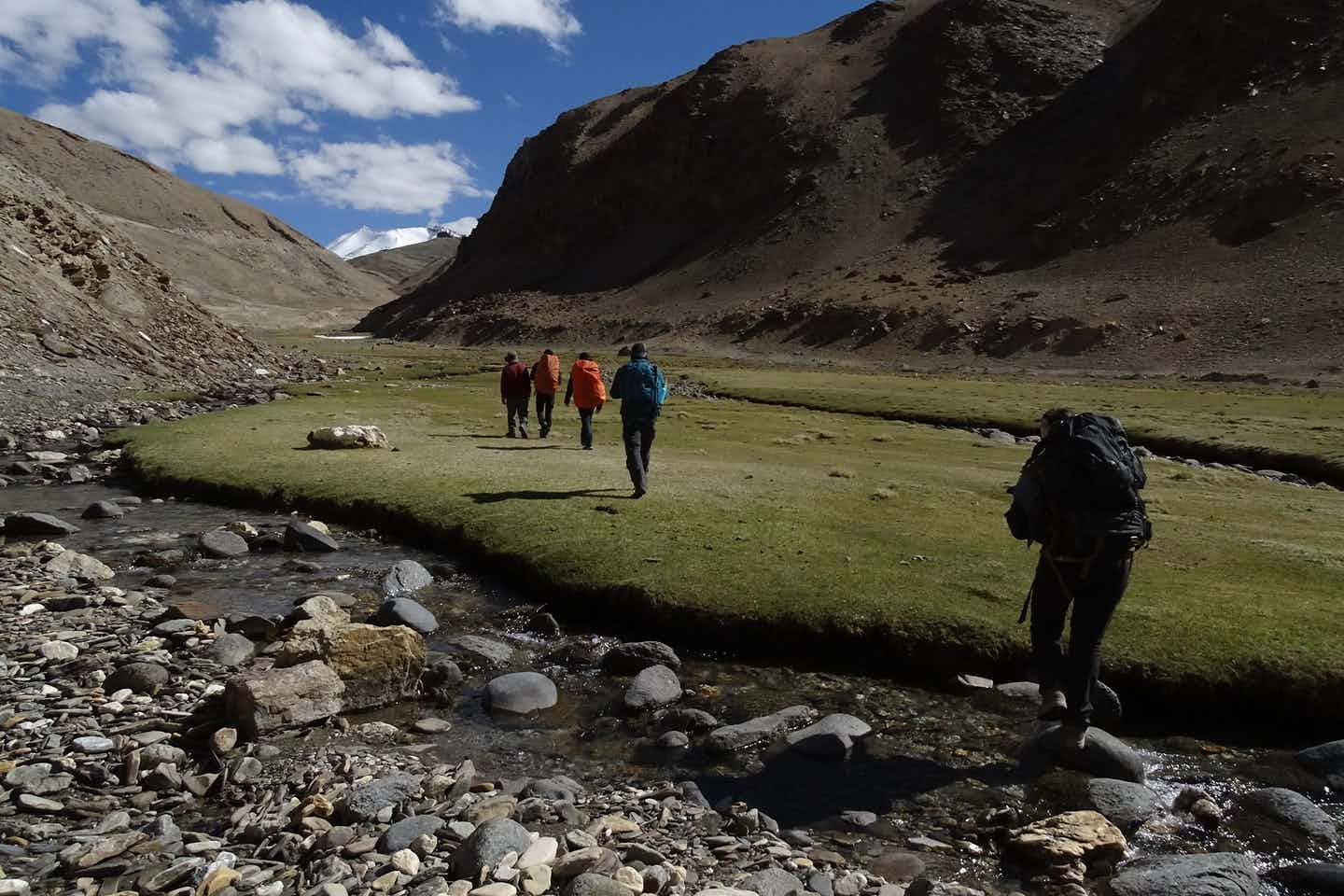 Trekkers crossing a stream in the Lato Vally, Ladakh, India.