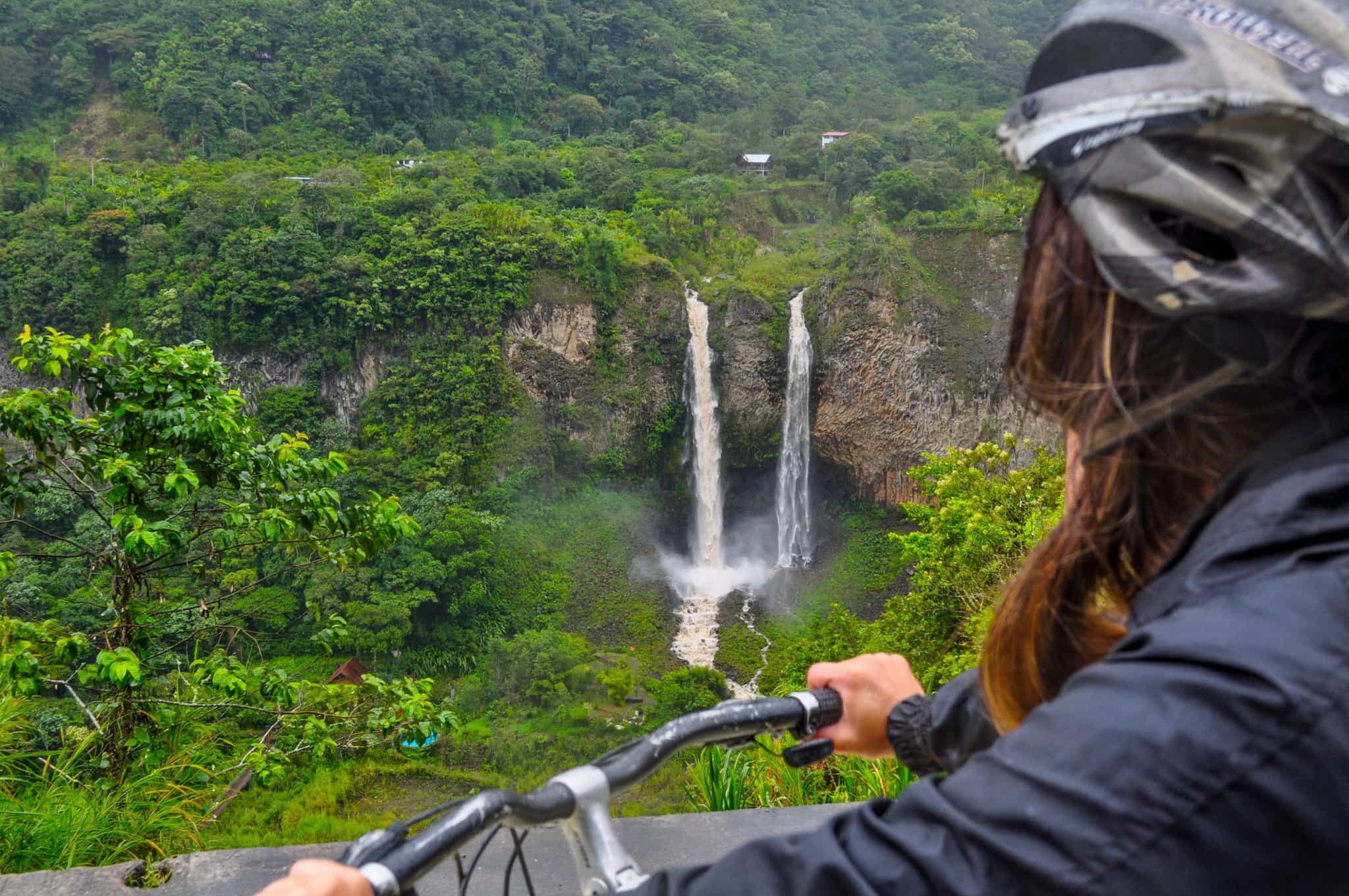 Cyclist overlooking a waterfall in the Baños cloud forest, Ecuador