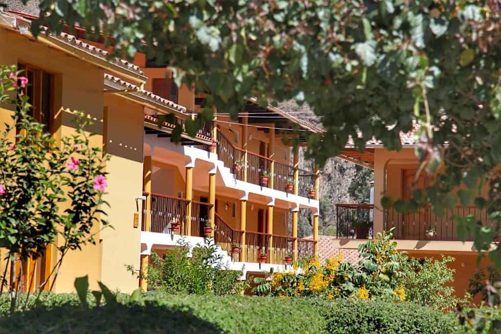 Picture of a yellow hotel lodging with balconies in front of a garden