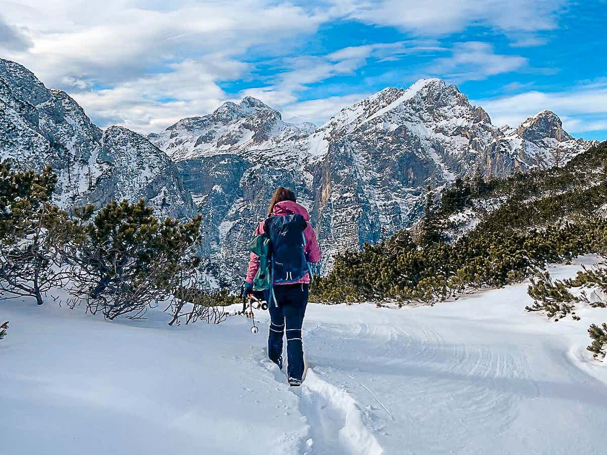 Female hiker in the snow heading towards the mountains of the Julian Alps in Slovenia.