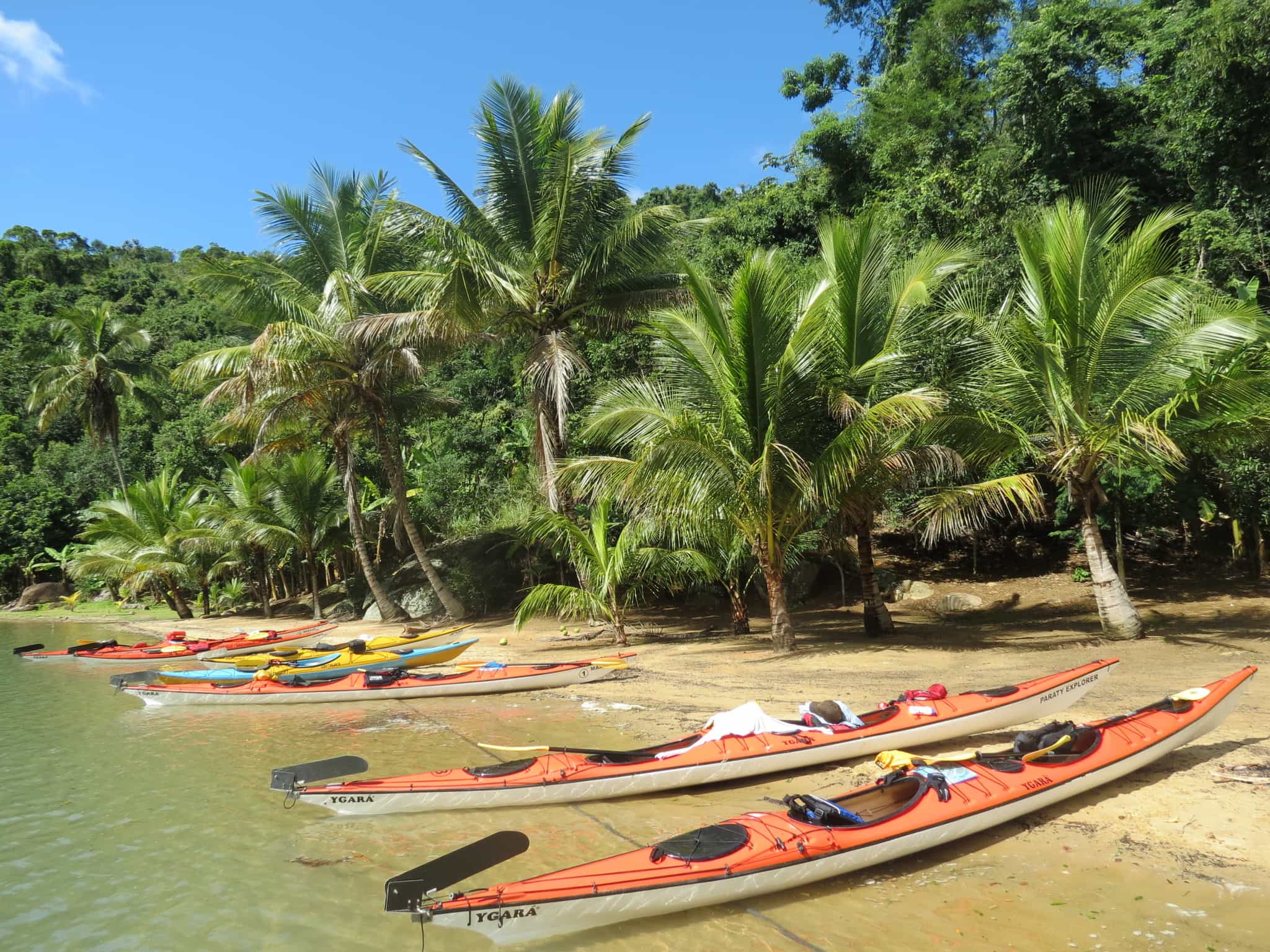 Kayaks on a tropical beach backed by palm trees in Paraty, Brazil