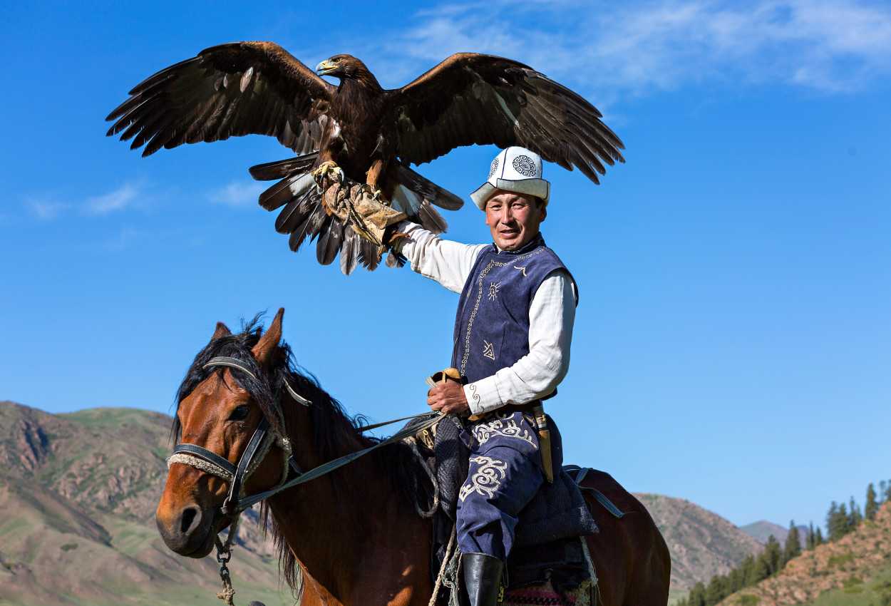 Eagle hunter on horseback holding his eagle in Kyrgyzstan. 