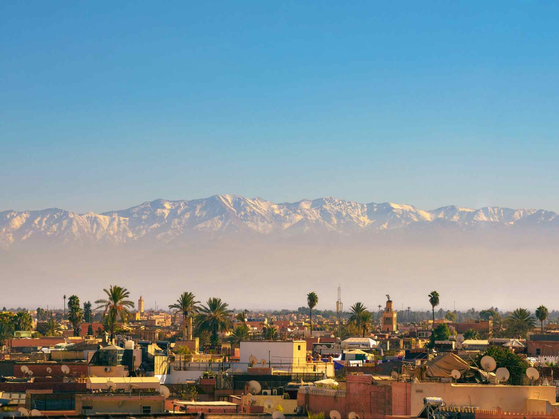 Marrakech city skyline in Morocco with snowy Atlas mountains in the background.