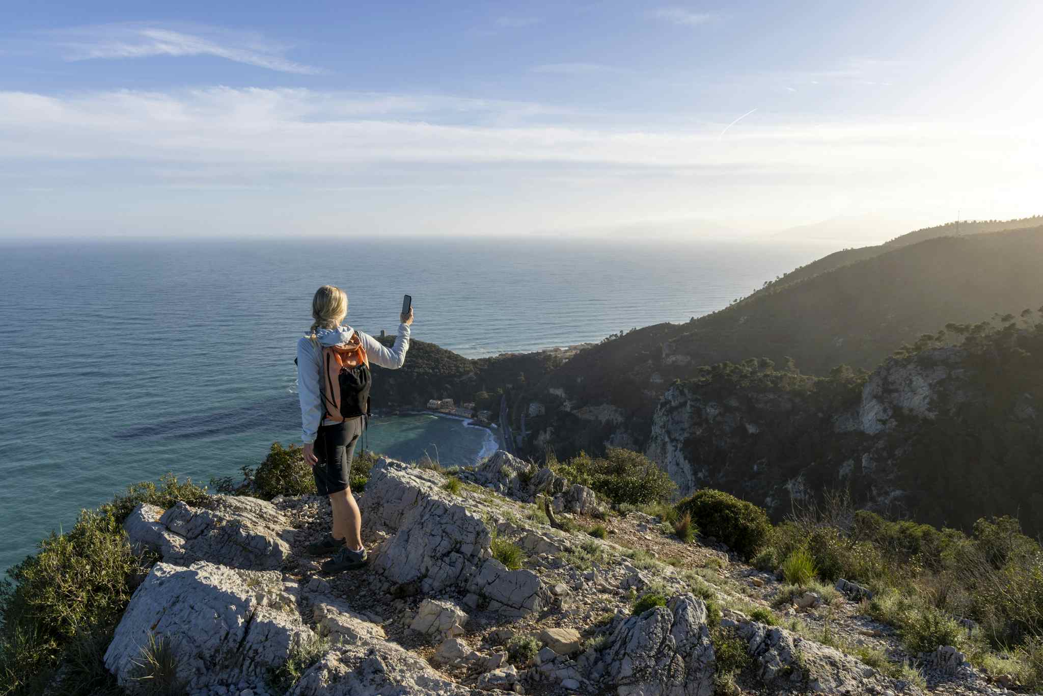 Hiker along the Ligurian trails, with a view of Bay of Saraceni. Liguria, Italy