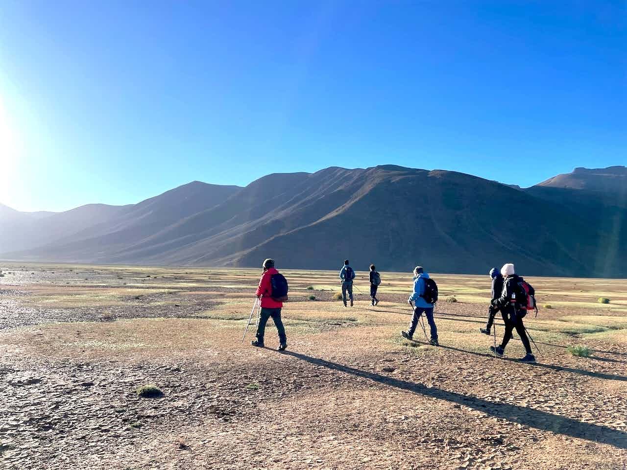 Hikers walking towards the sunlight with mountain views, Morocco.