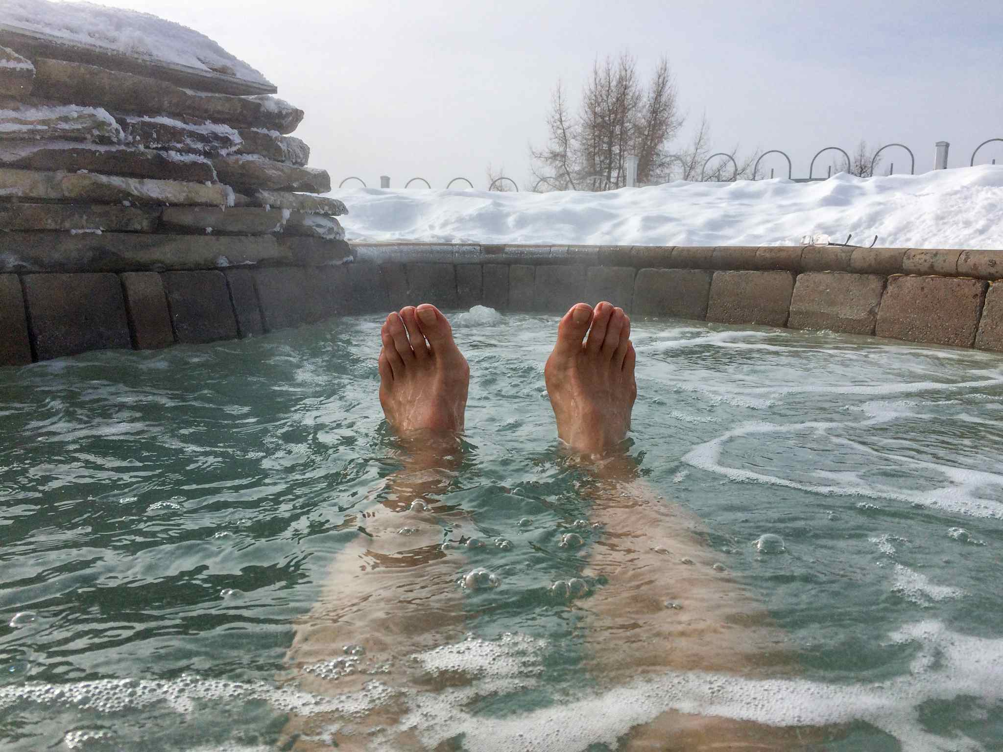 Man lying in hot springs with snow on the edge