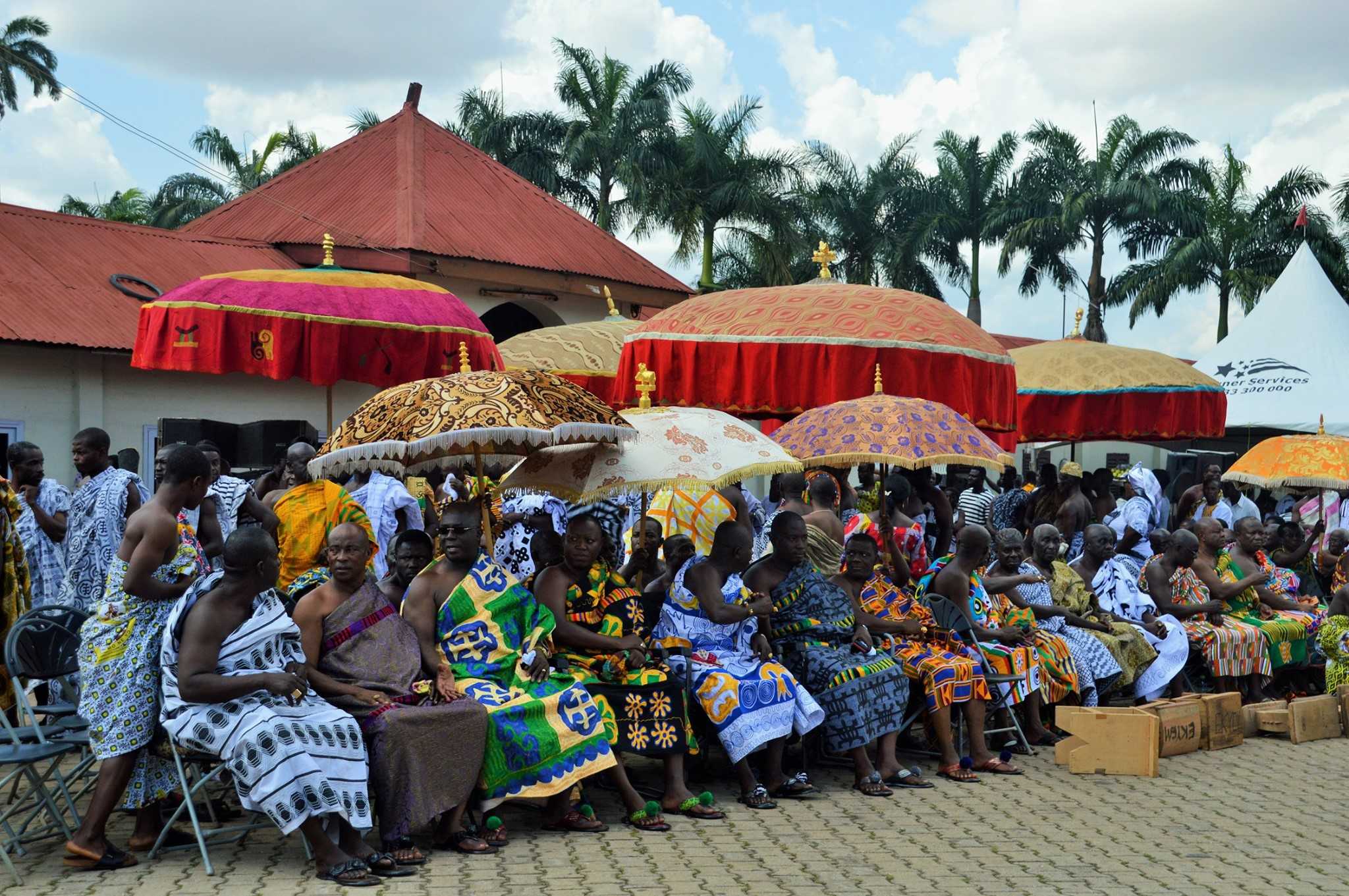 Seated attendees at the Akwasidae Festival in Kumasi, Ghana, under colourful decorative umbrellas.