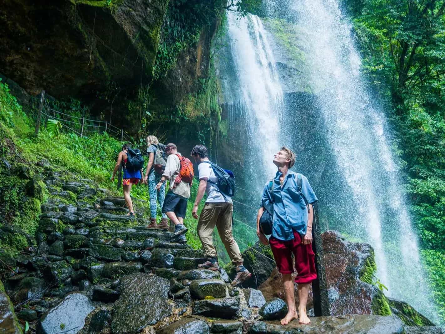 Group of travellers walking up the steps behind a waterfall