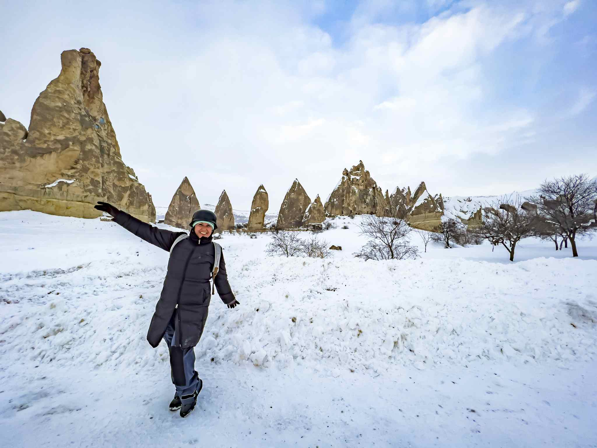 Smiling female tourist in snowy Cappadocia. Photo: GettyImages-1458094812
