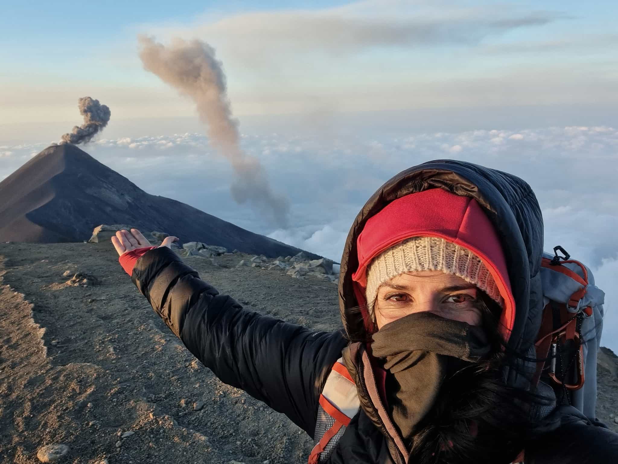 Hiker at the summit of Acatenango with view of Fuego erupting in the background. Photo: Marta Marinelli