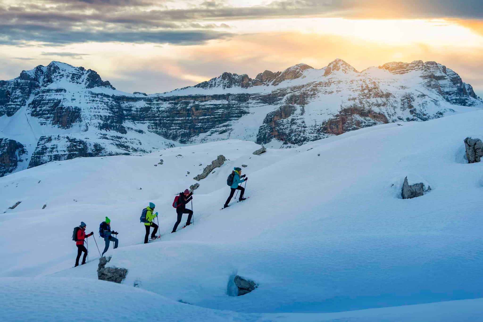 Row of hikers snowshoeing up a trail in the Dolomites, Italy.