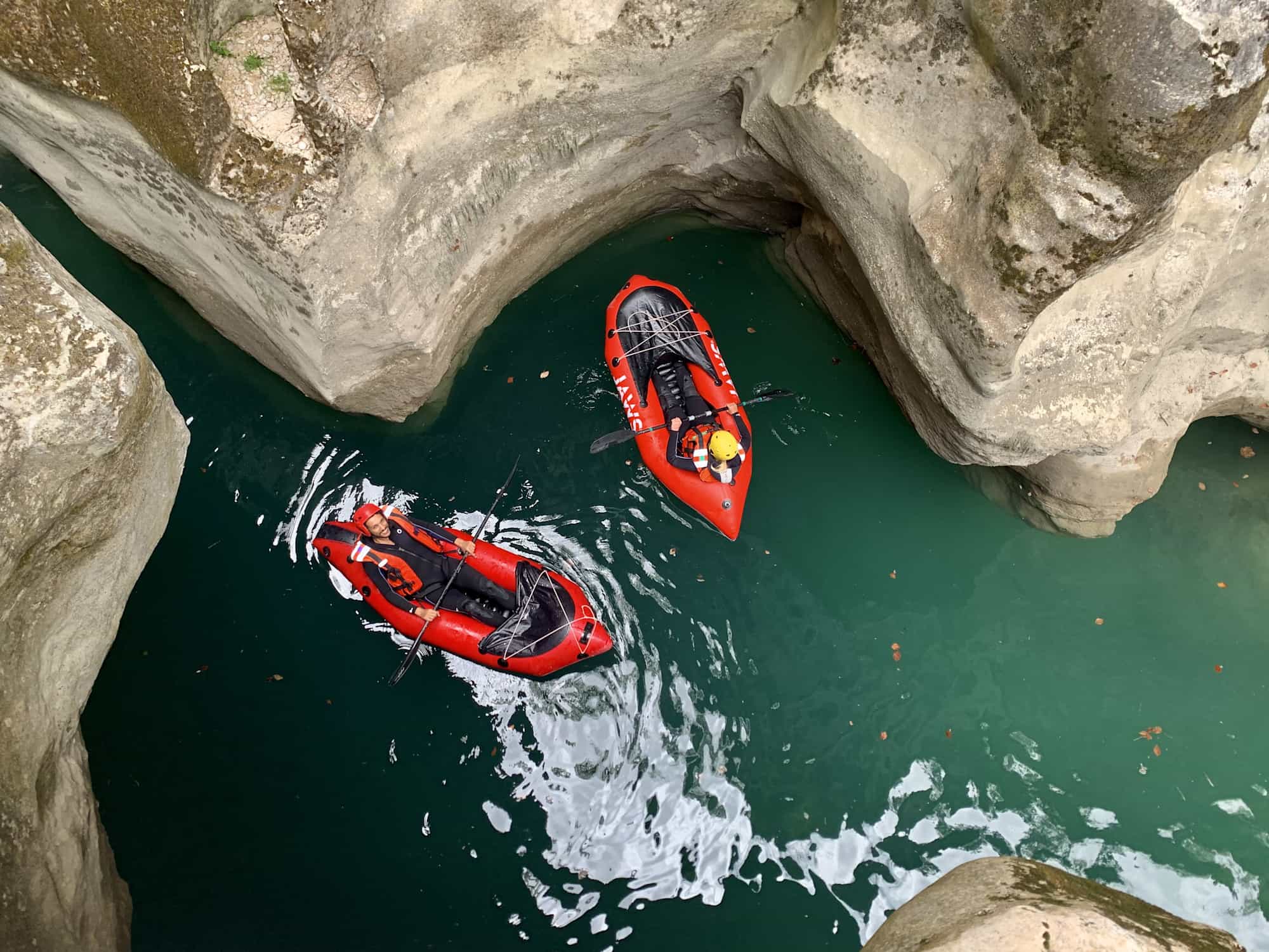 Two people packrafting in a canyon.