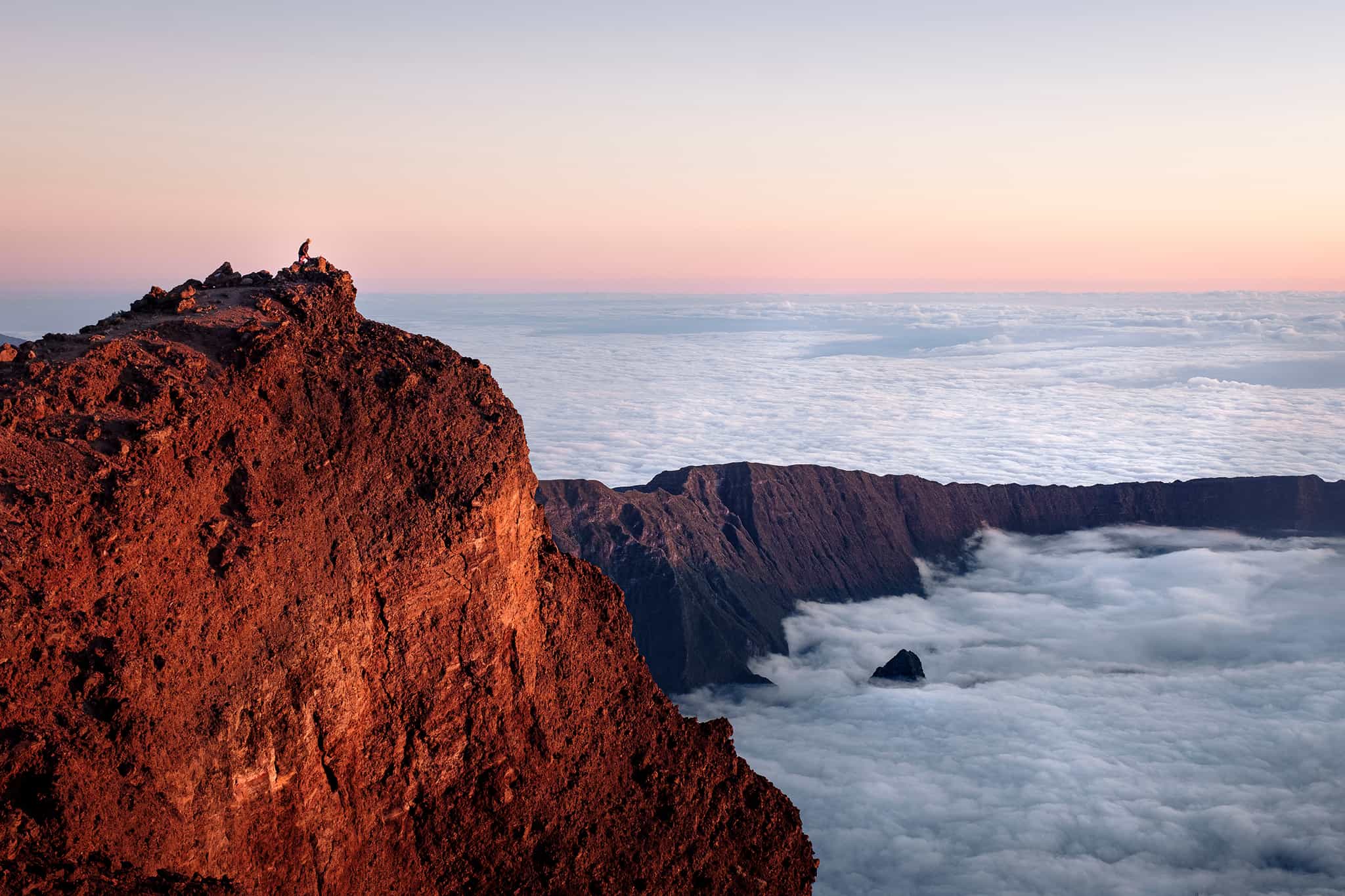 Hiker watching the sunrise over Piton des Neiges, Reunion