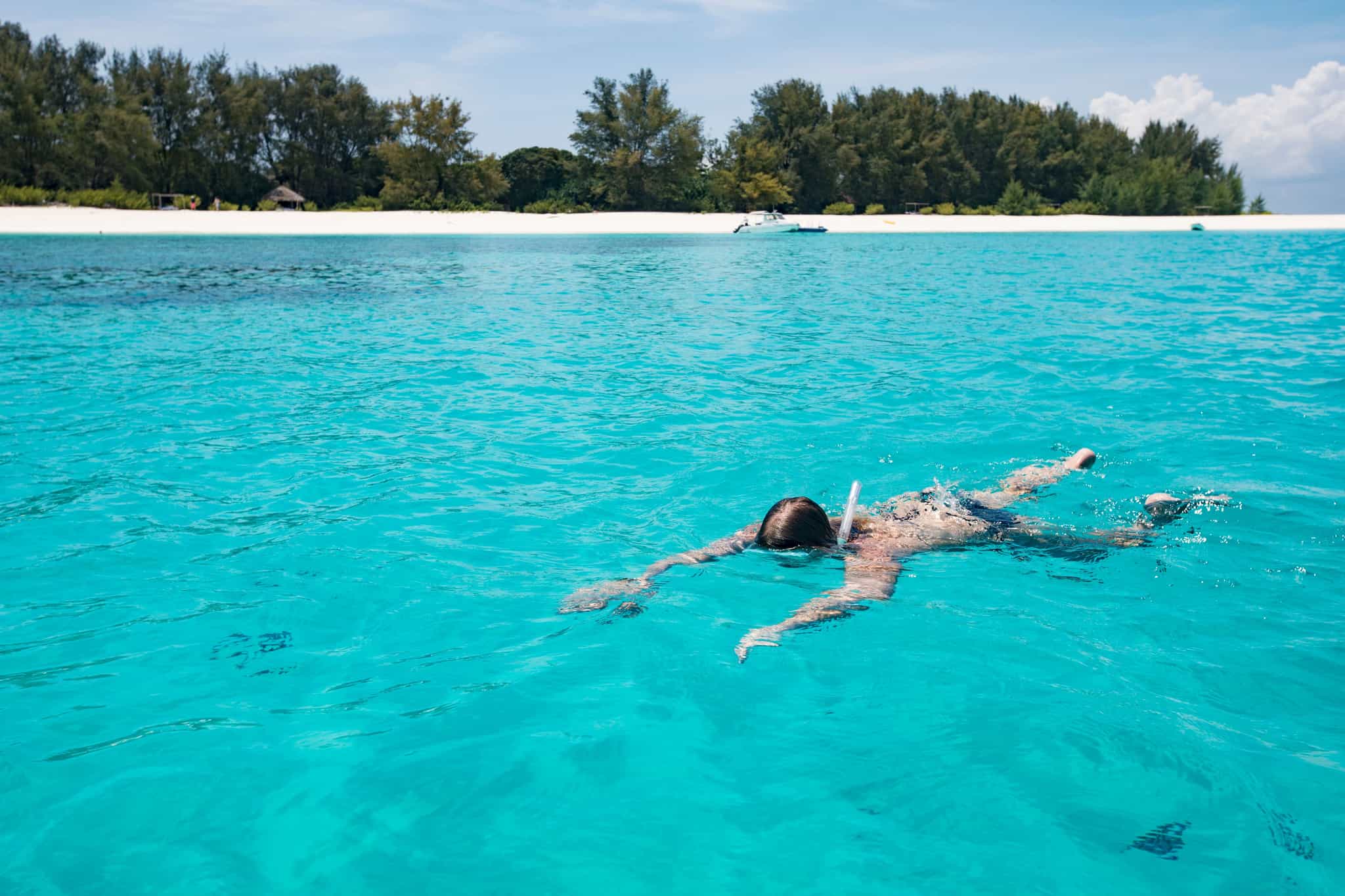 Woman snorkelling the turquoise waters off the coast of Zanzibar, Tanzania.