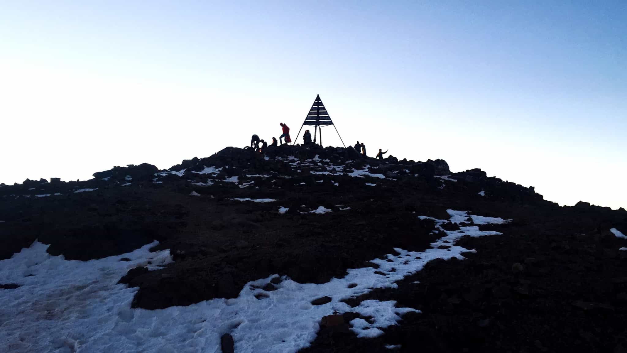 A silhouette of hikers at the summit of Mount Toubkal in the Atlas Mountains, Morocco.