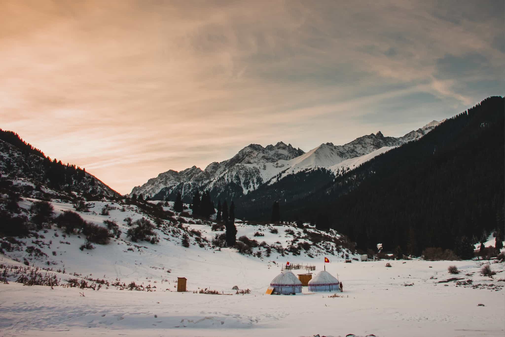 View of the yurt camp in the snowy valley below high mountains