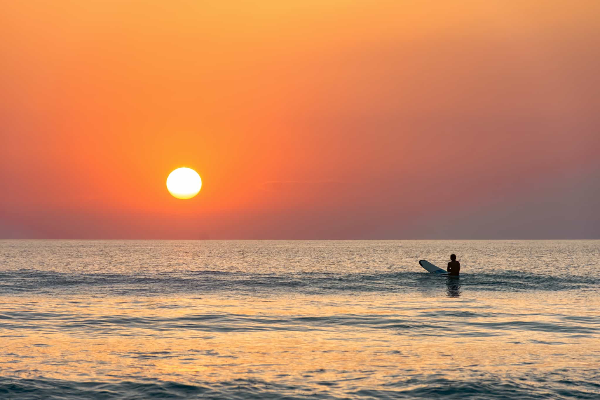 Surfer waiting for a wave at sunset in Bali, Indonesia